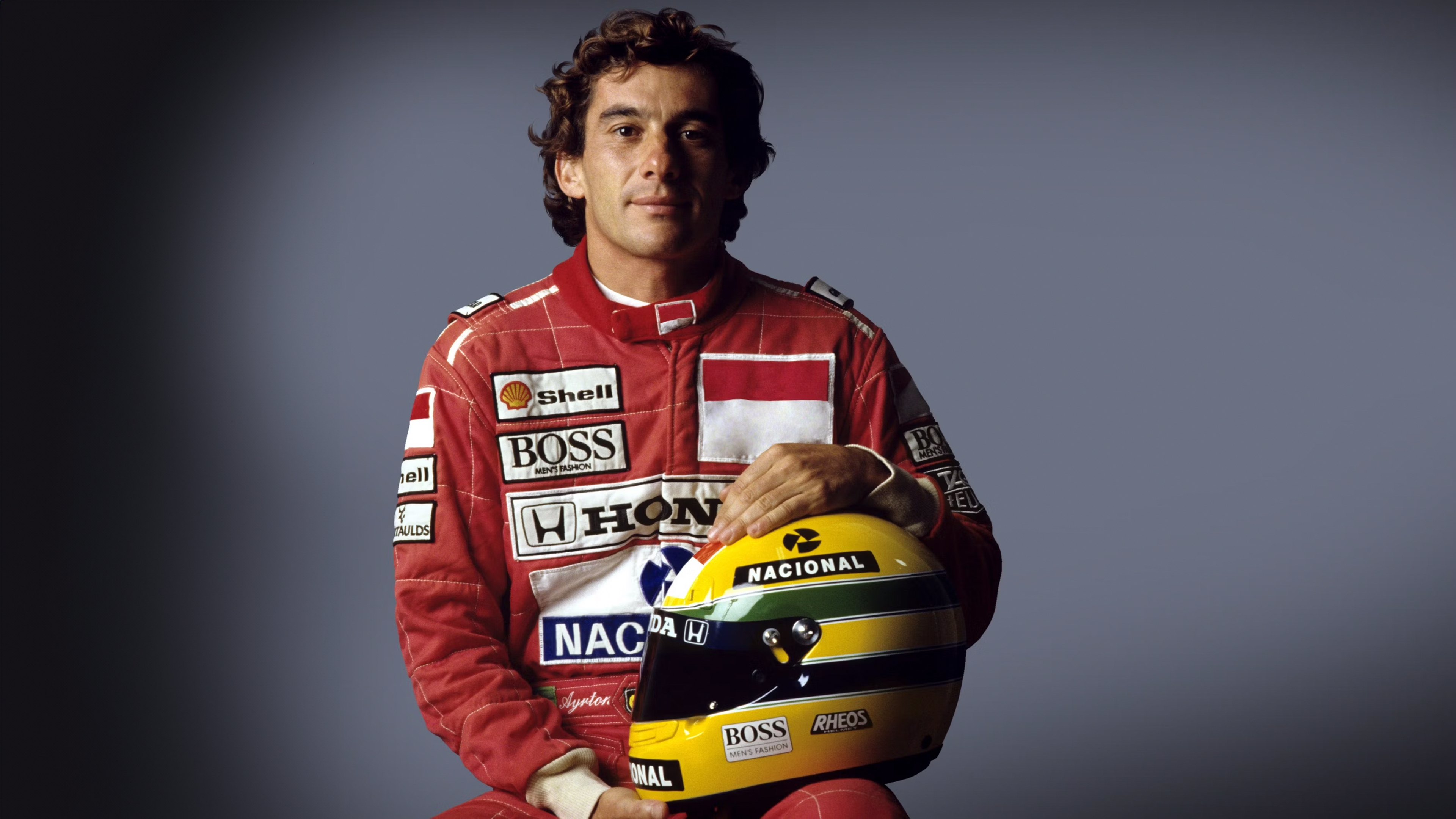 A Formula 1 driver wearing a racing suit with the colors of the Brazilian flag, looking ready for a race.