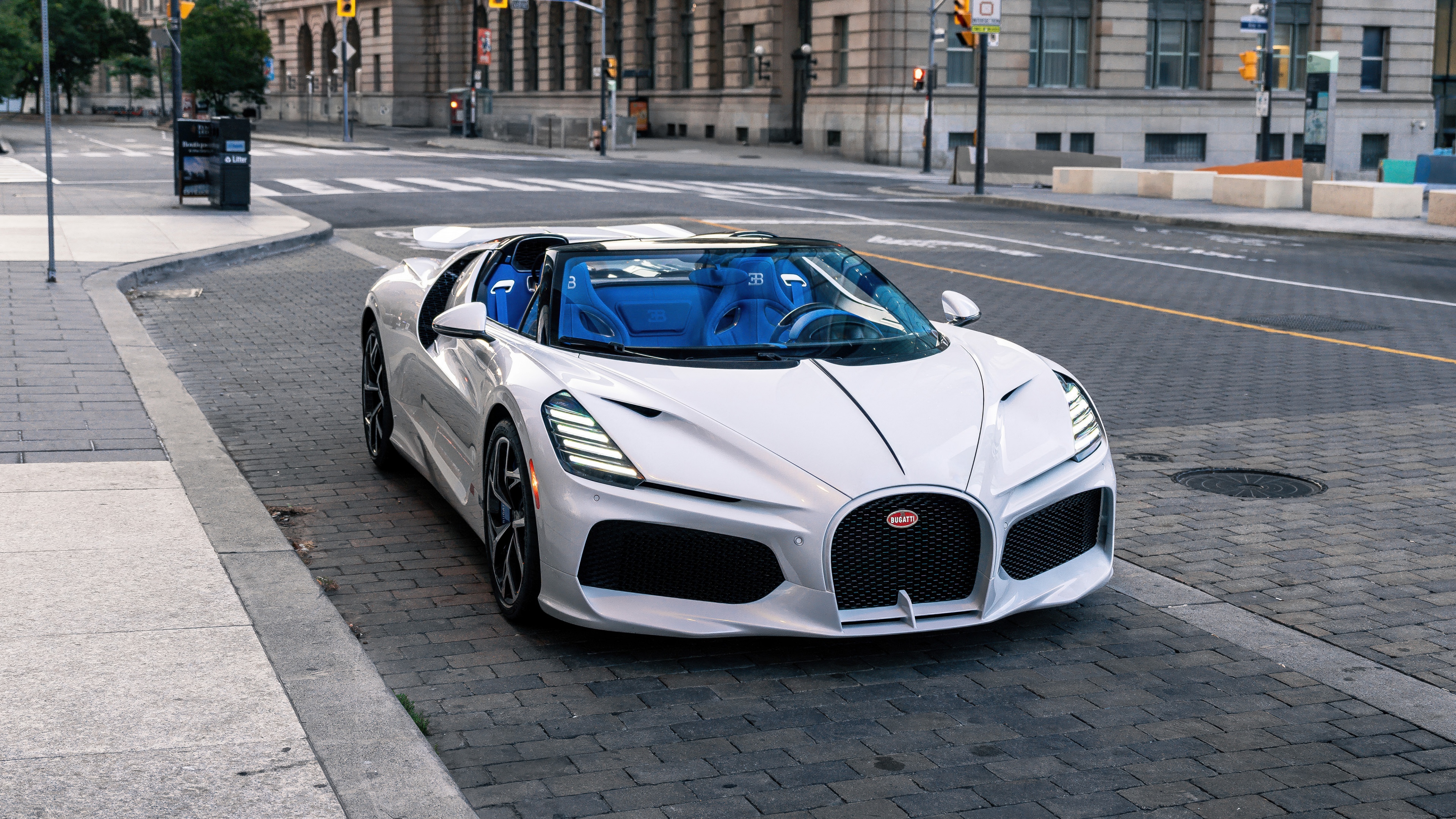 A white Bugatti W16 Mistral hypercar driving on a city road in Toronto.