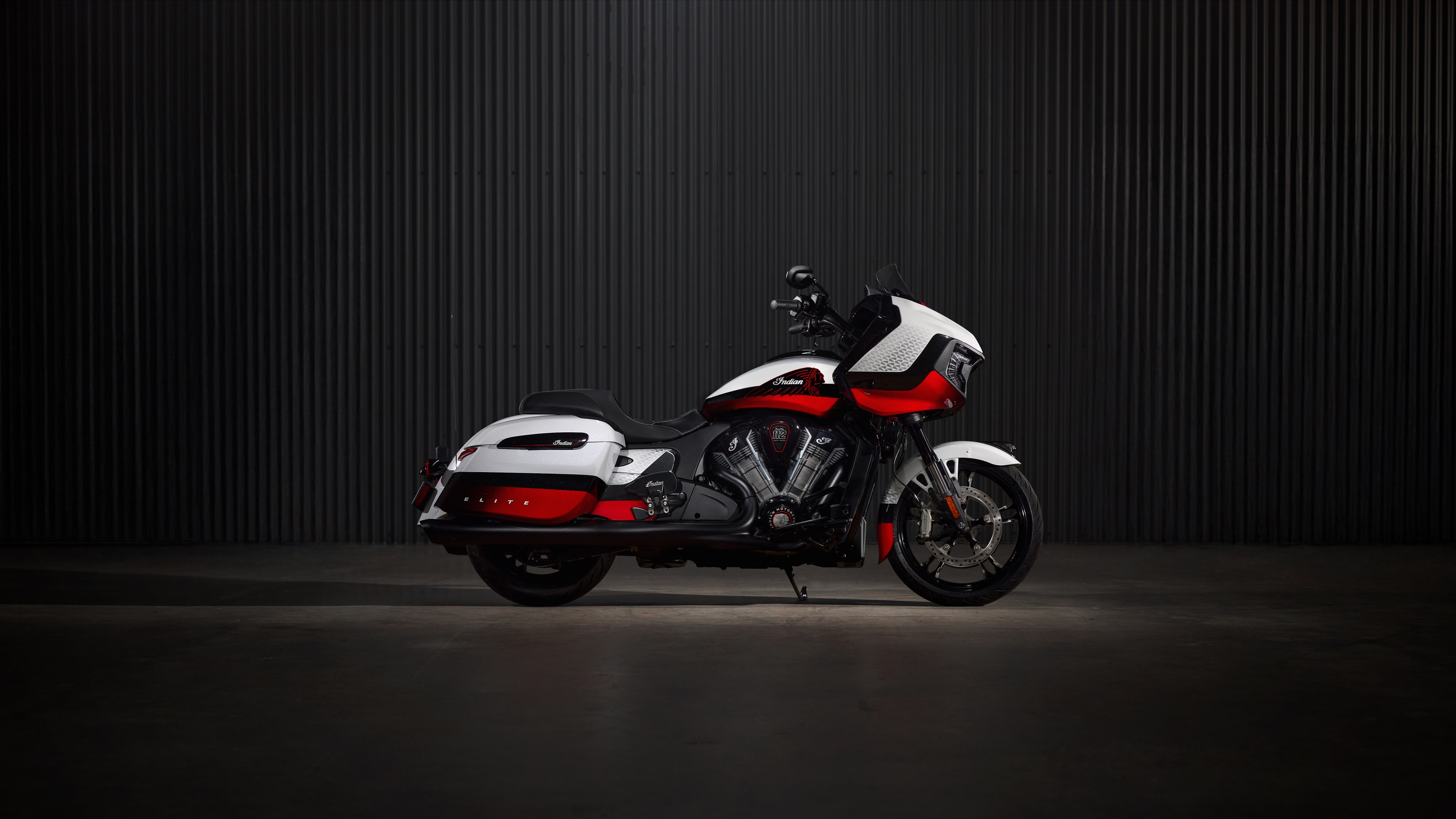 A high-detail, cinematic close-up of an Indian Chieftain Elite cruiser motorcycle featuring chrome accents against a dark, moody background.