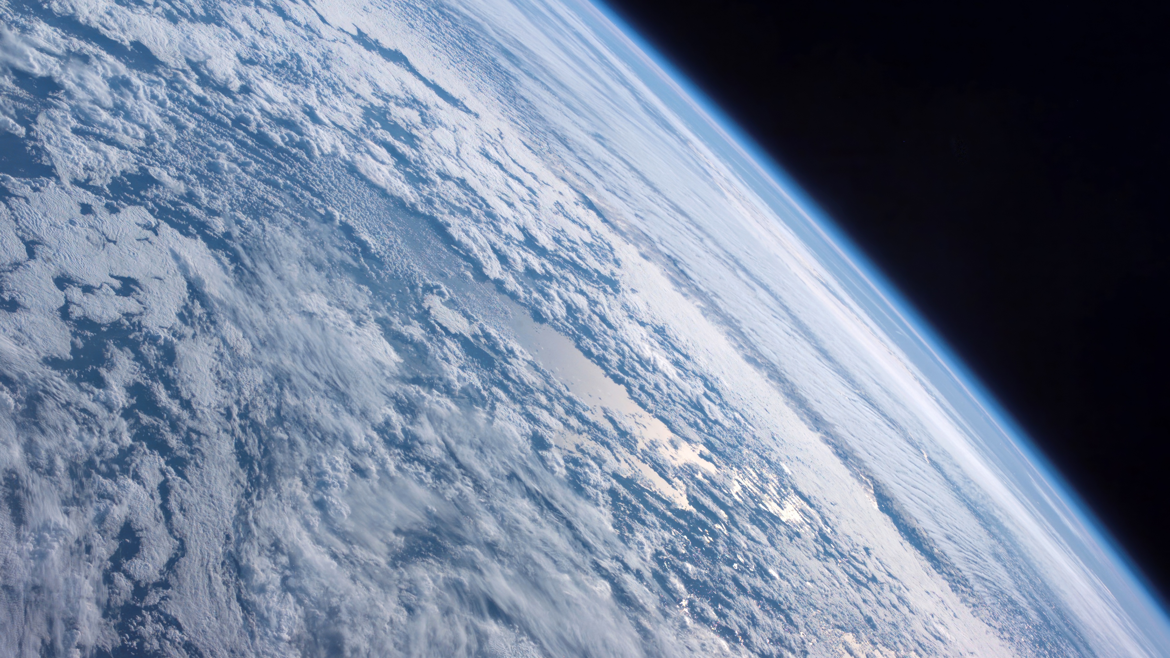 A high-resolution 5K cinematic view of Planet Earth in orbit, featuring swirling clouds and the atmospheric glow, styled after Mac OS X Mountain Lion.