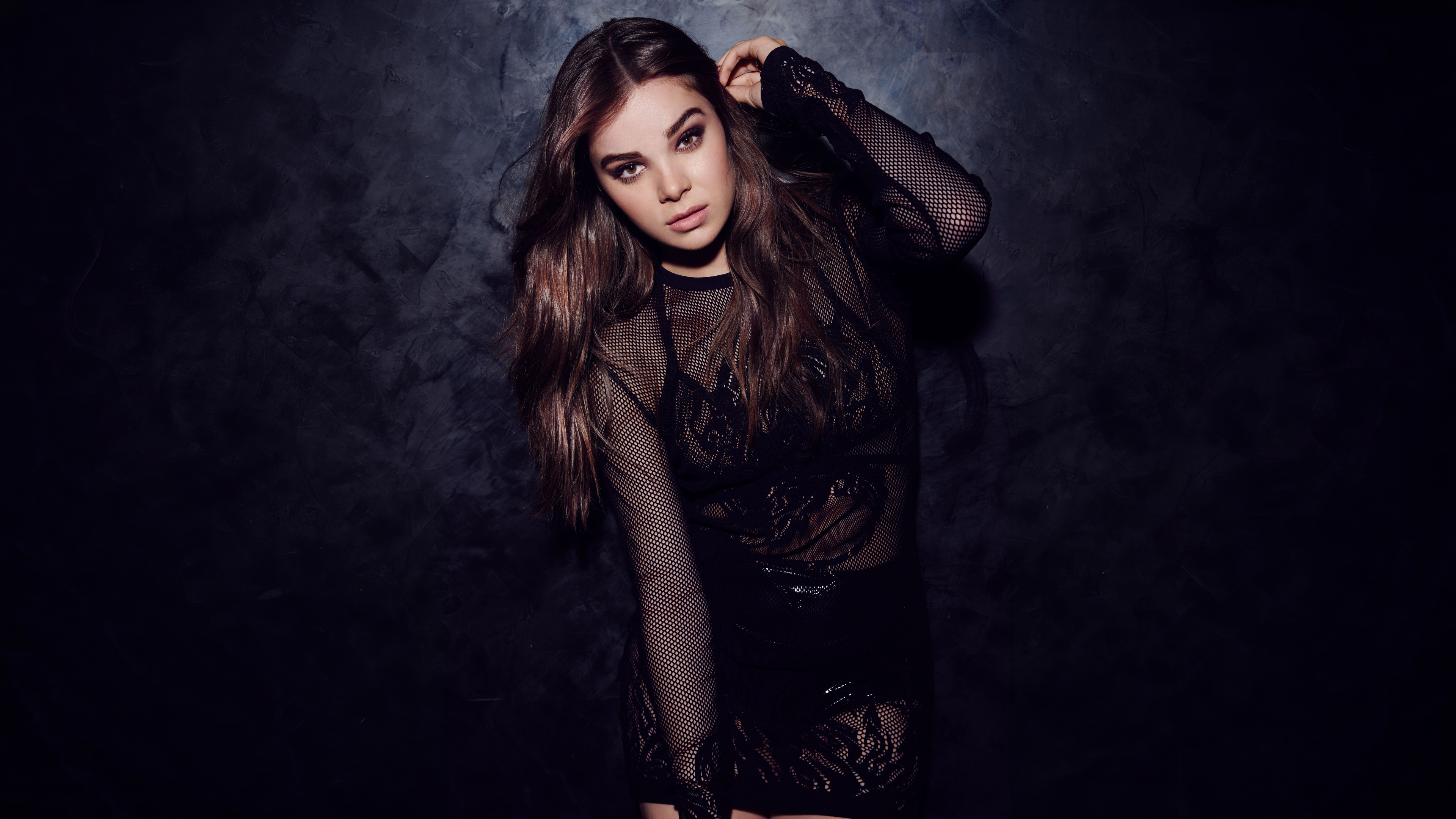 A high-detail portrait of Hailee Steinfeld posing in a black dress against a dark, moody background.