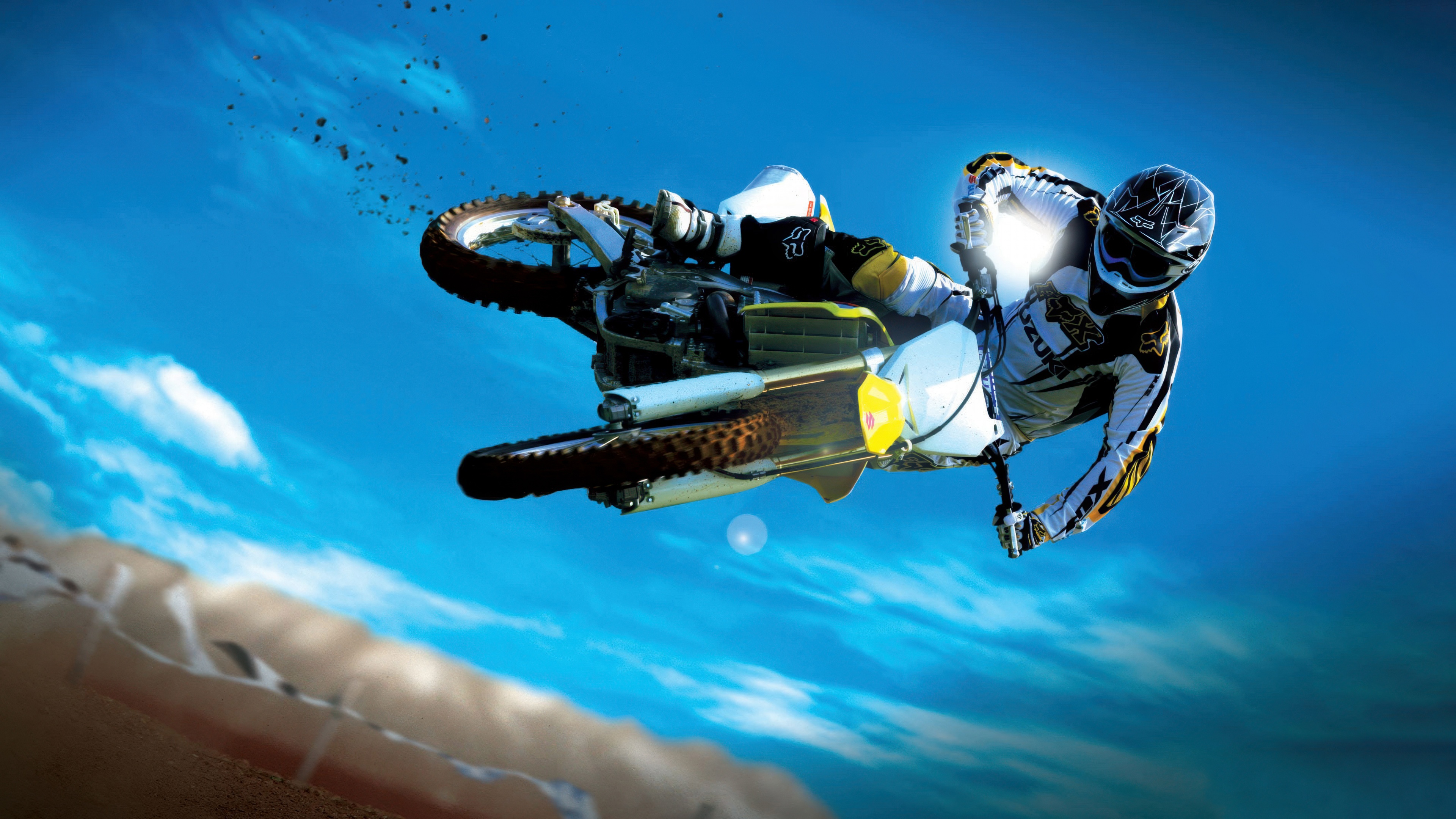 A motocross rider performing a spectacular mid-air stunt on a dirt bike with flying dirt.