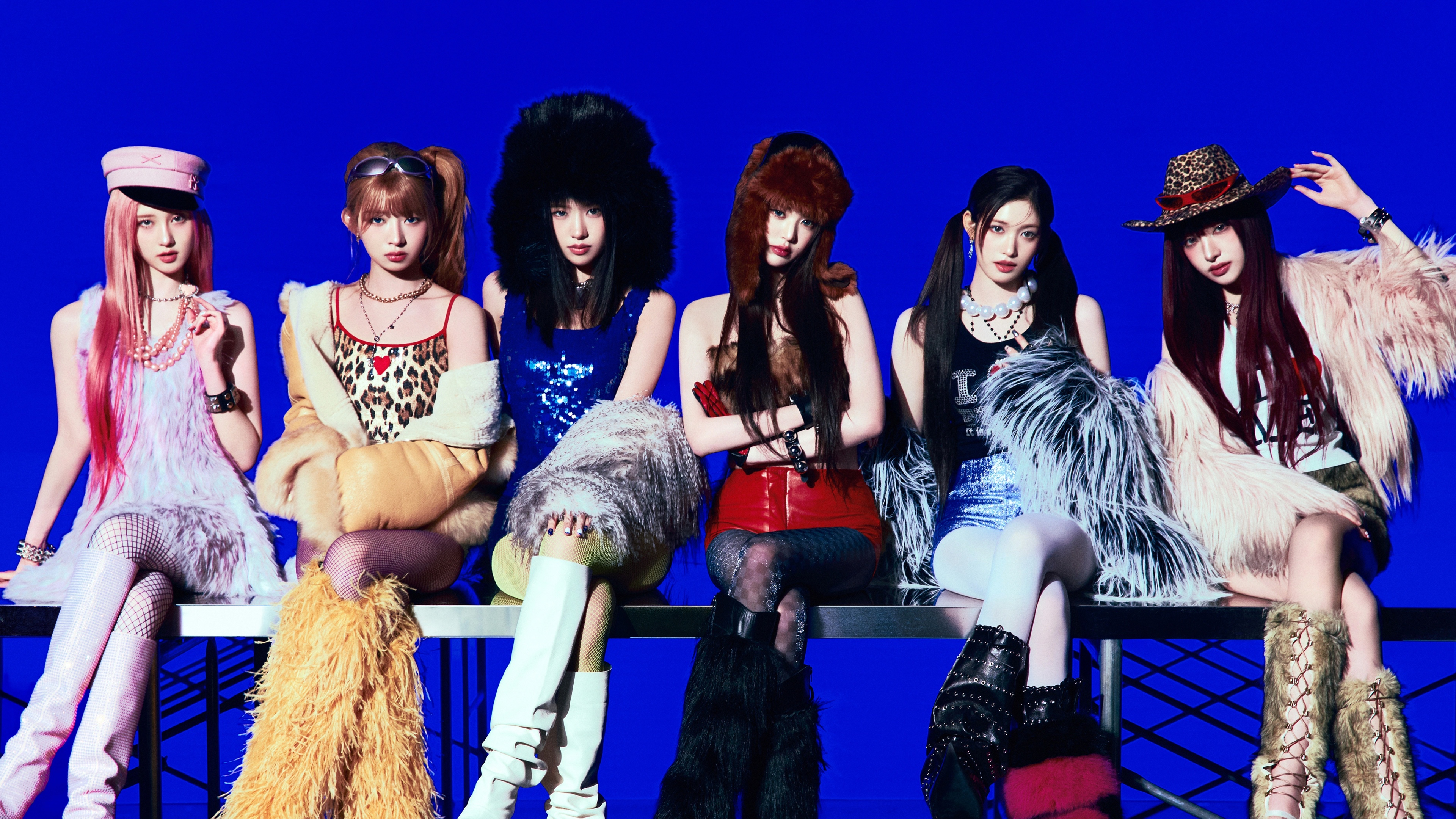 K-pop group IVE members posing against a bright blue background.
