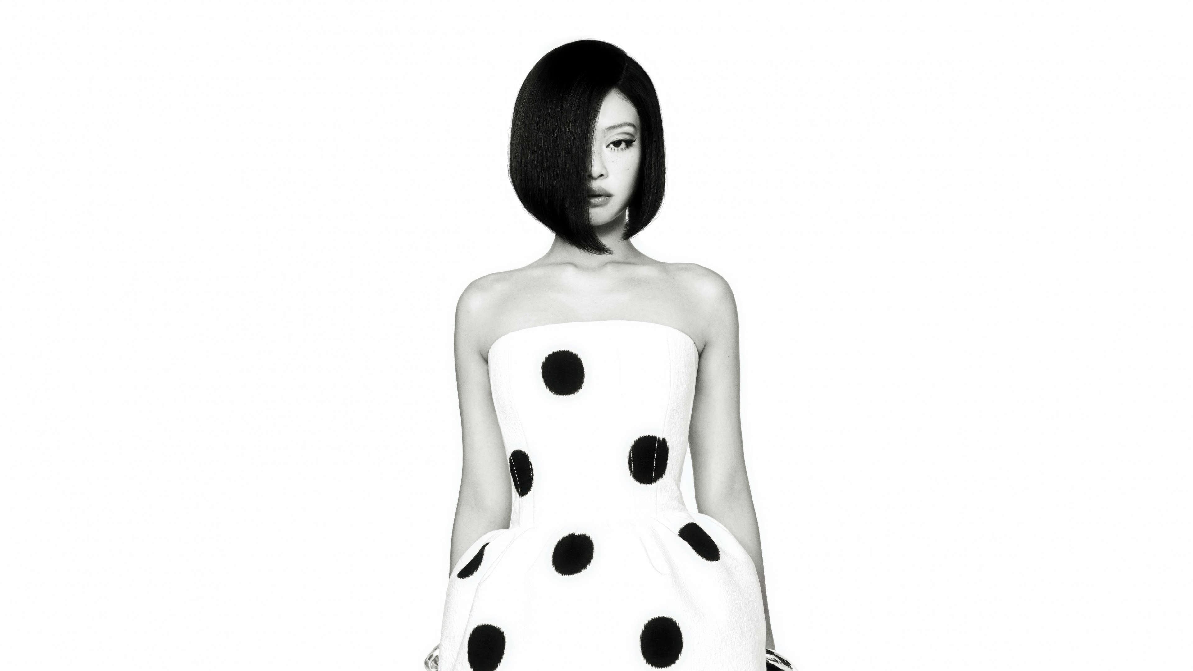 A high-contrast, monochrome close-up portrait of Jennie Kim against a clean white background, styled for a fashion magazine.