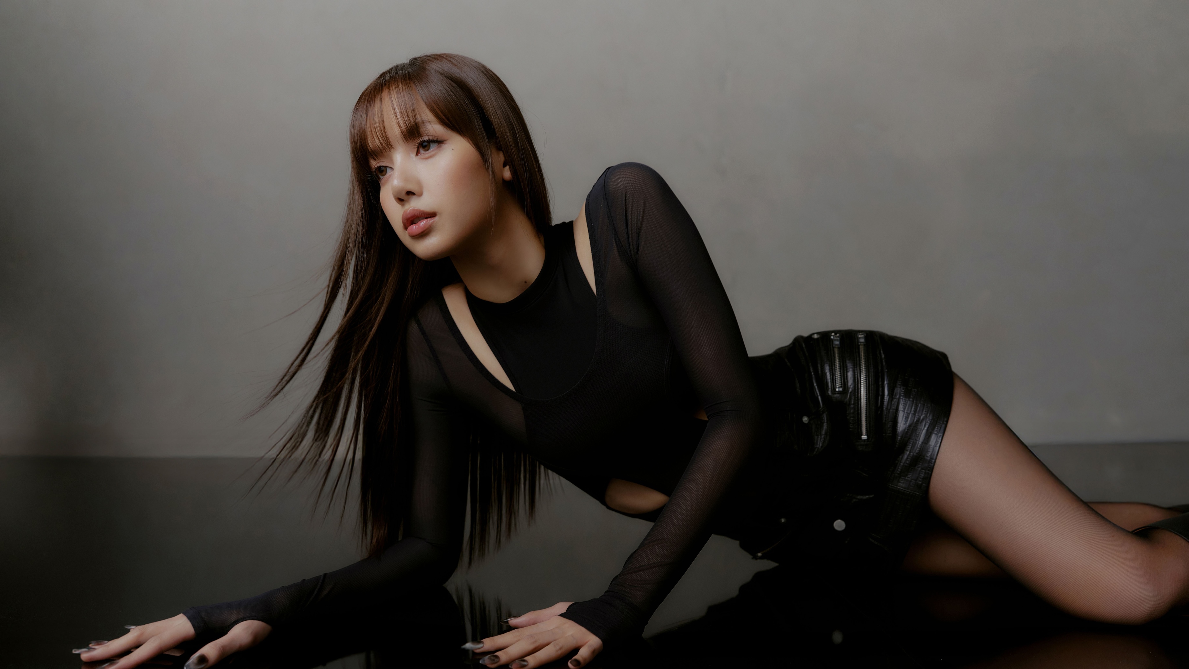 A cinematic professional photoshoot of Lisa wearing an elegant black dress in a dark, moody setting.