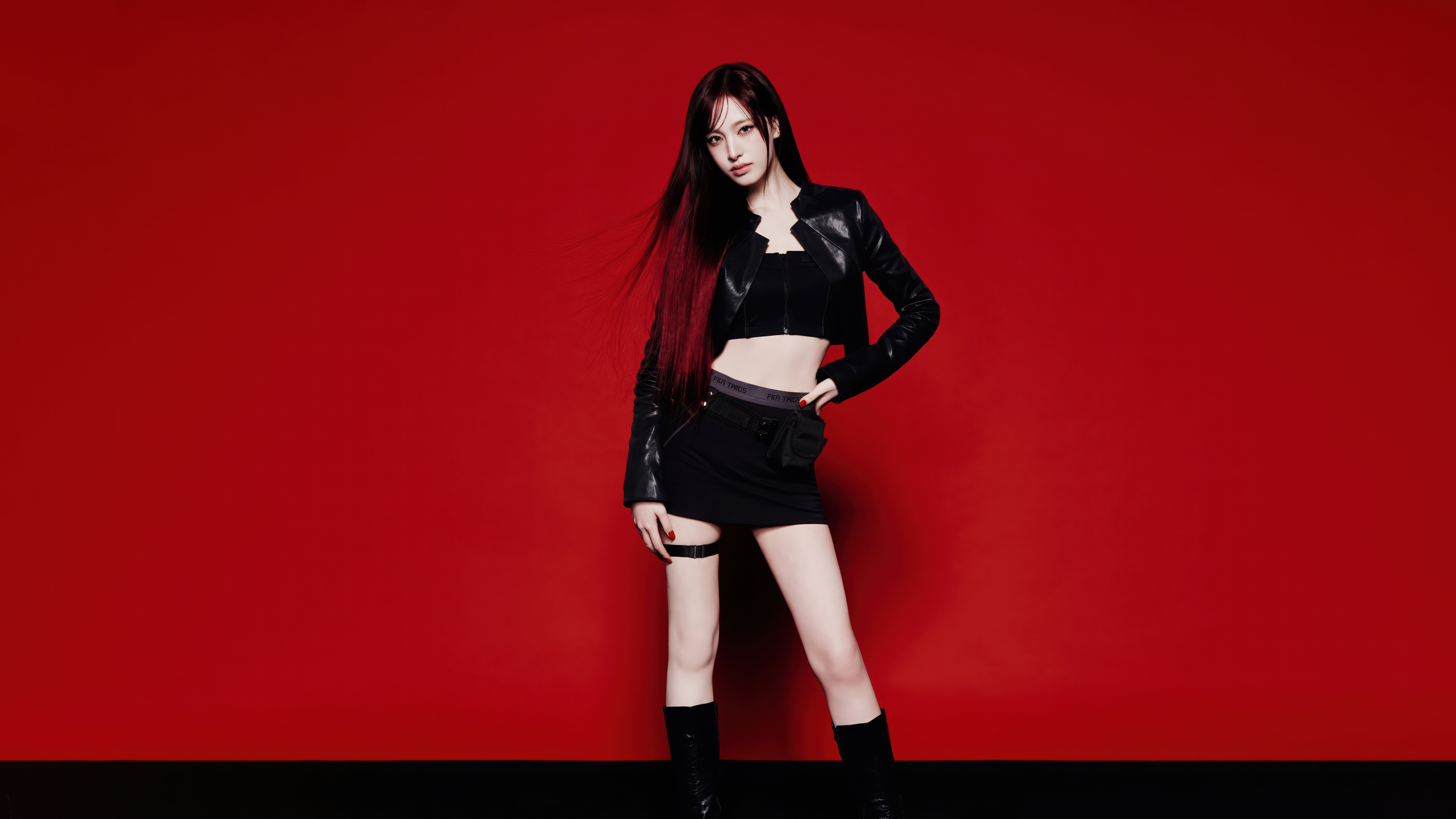 Liz from the K-pop group IVE wearing a stylish black dress against a solid red background