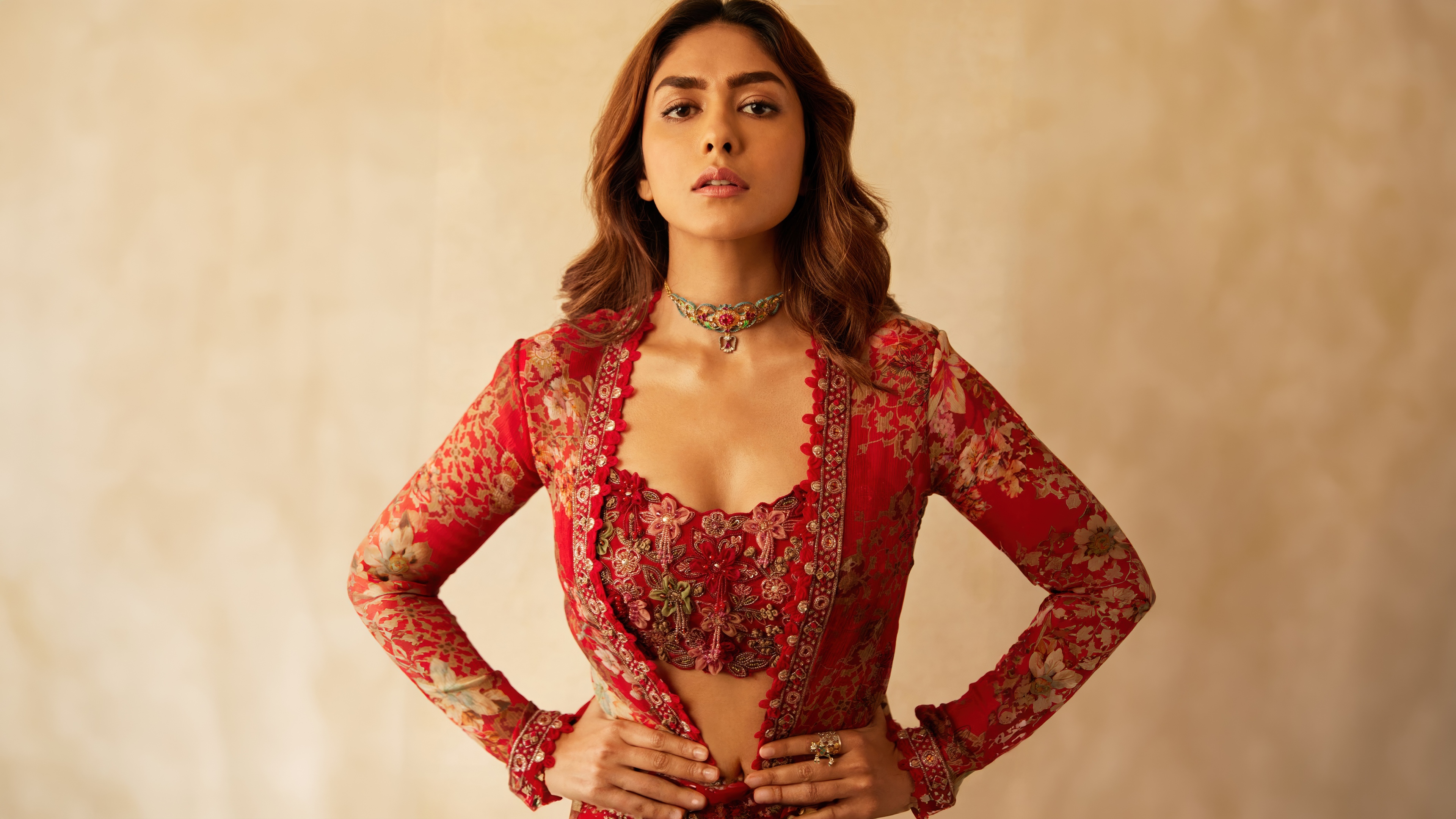 Indian actress Mrunal Thakur posing in a beautiful red dress with floral patterns.