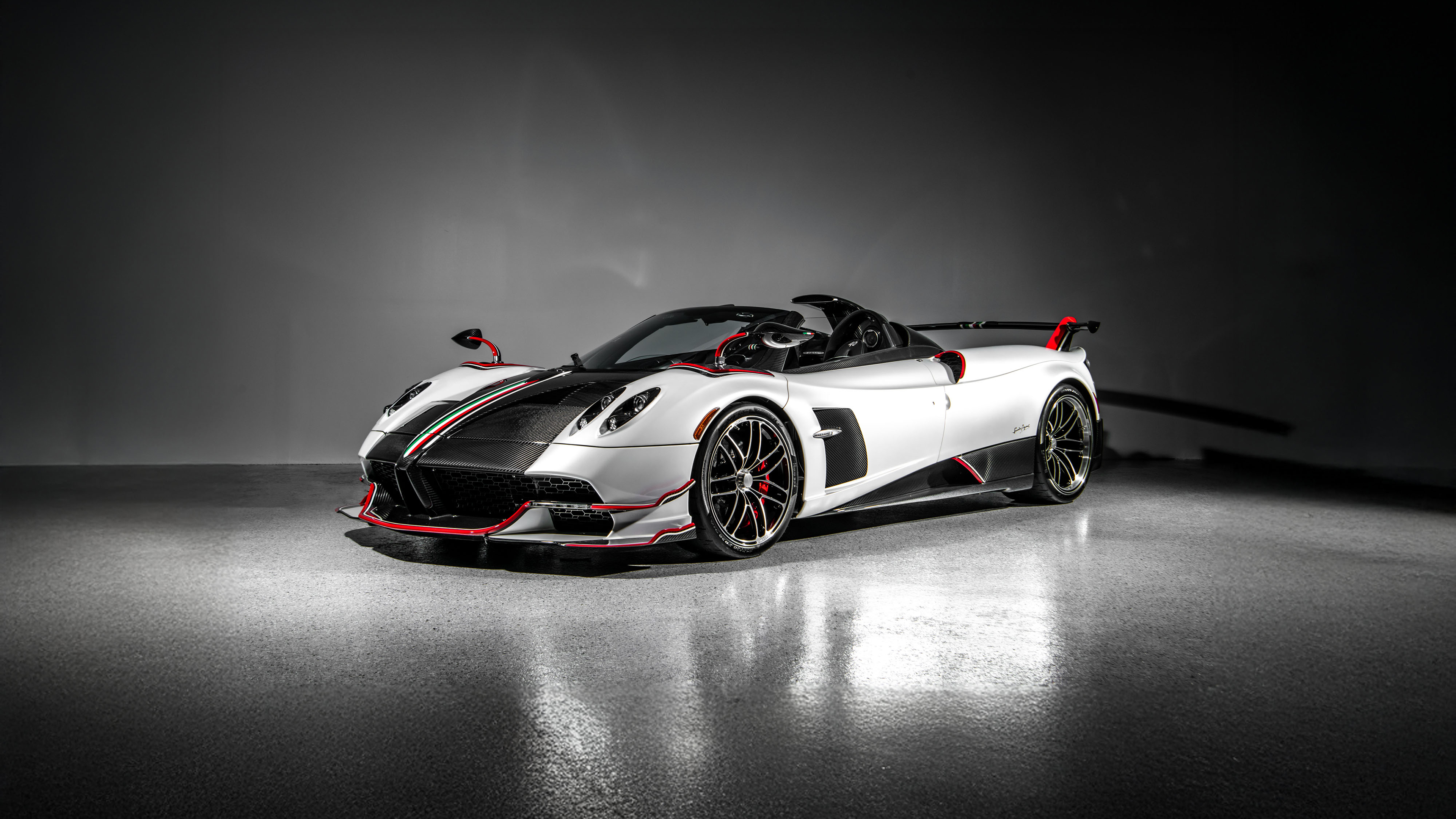 A high-detail close-up of a Pagani Huayra Roadster hypercar against a dark, moody background.