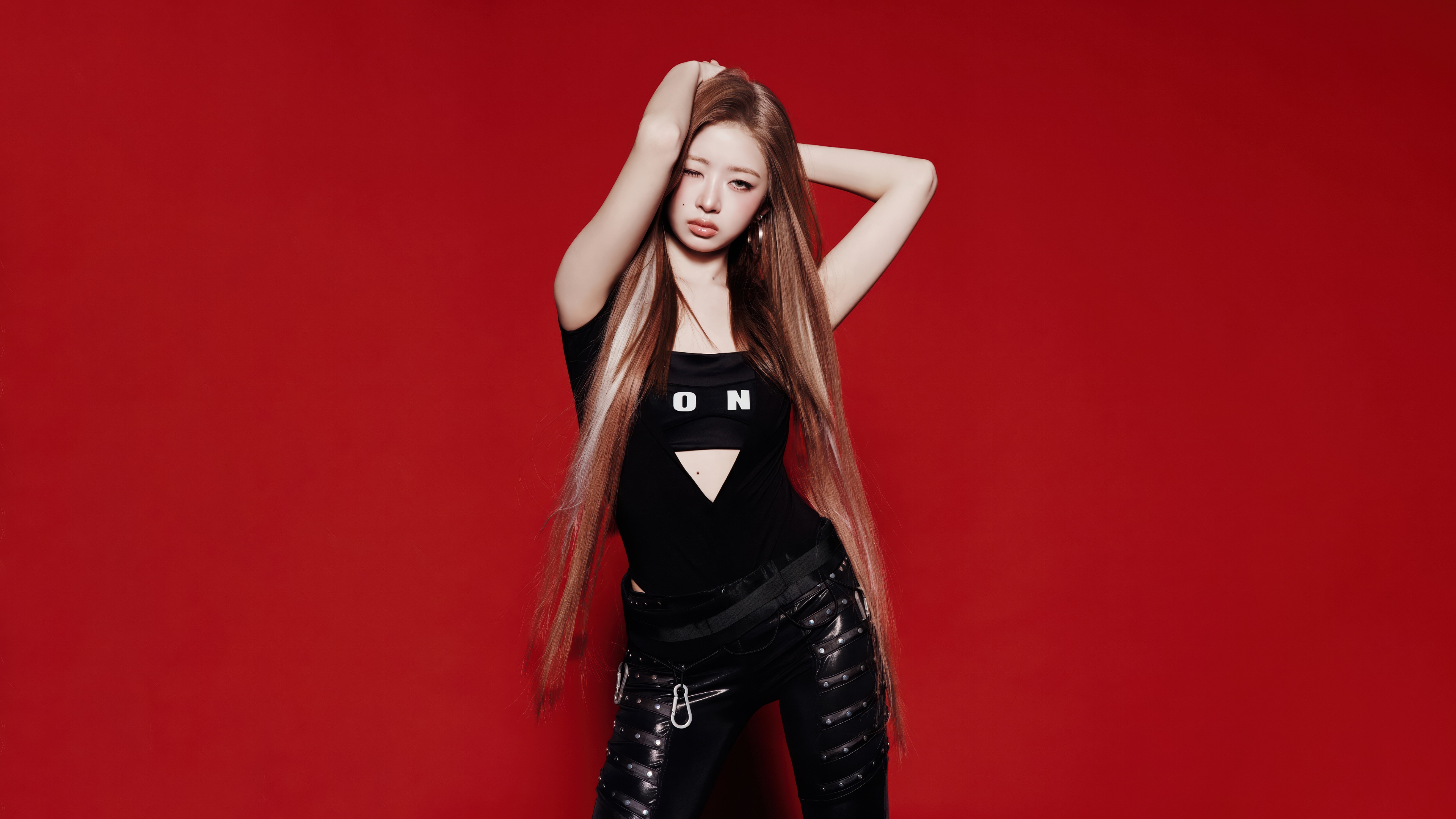 Rei from the K-pop group IVE wearing a black dress against a vibrant red background