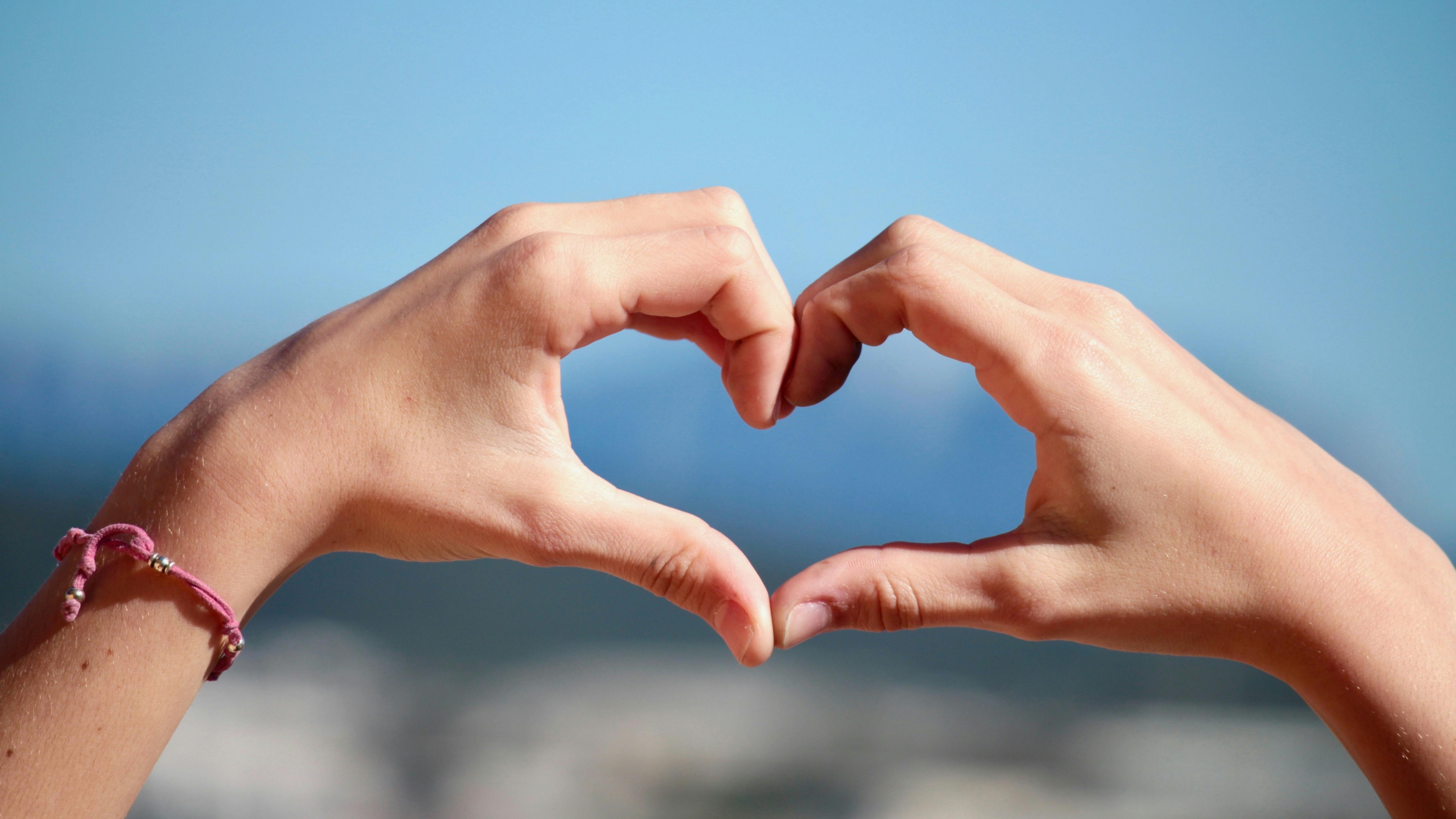 Close-up of hands forming a heart shape with a beautiful bokeh light background