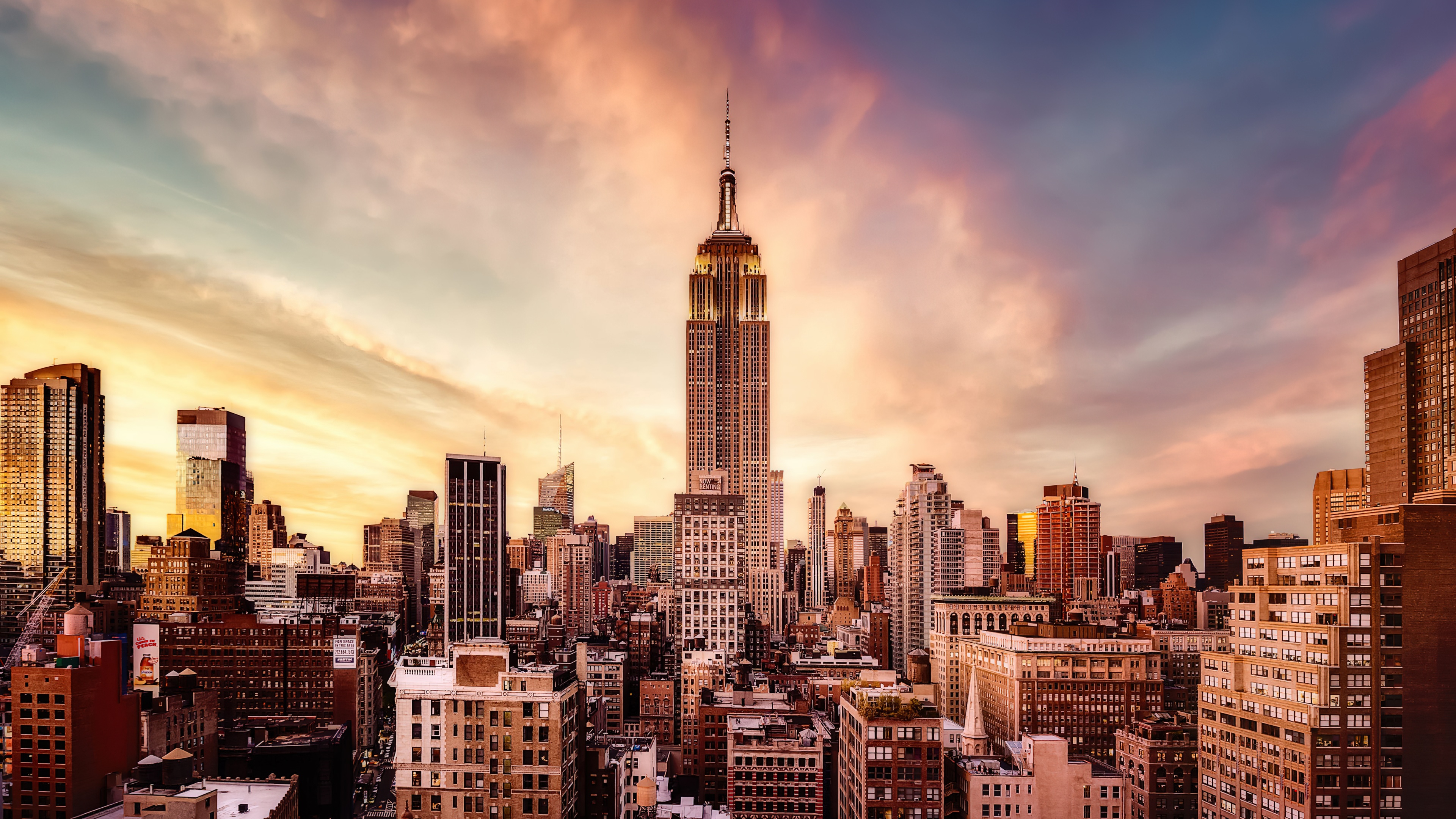 The Empire State Building in New York City during a beautiful sunset with warm orange and pink hues in the sky.