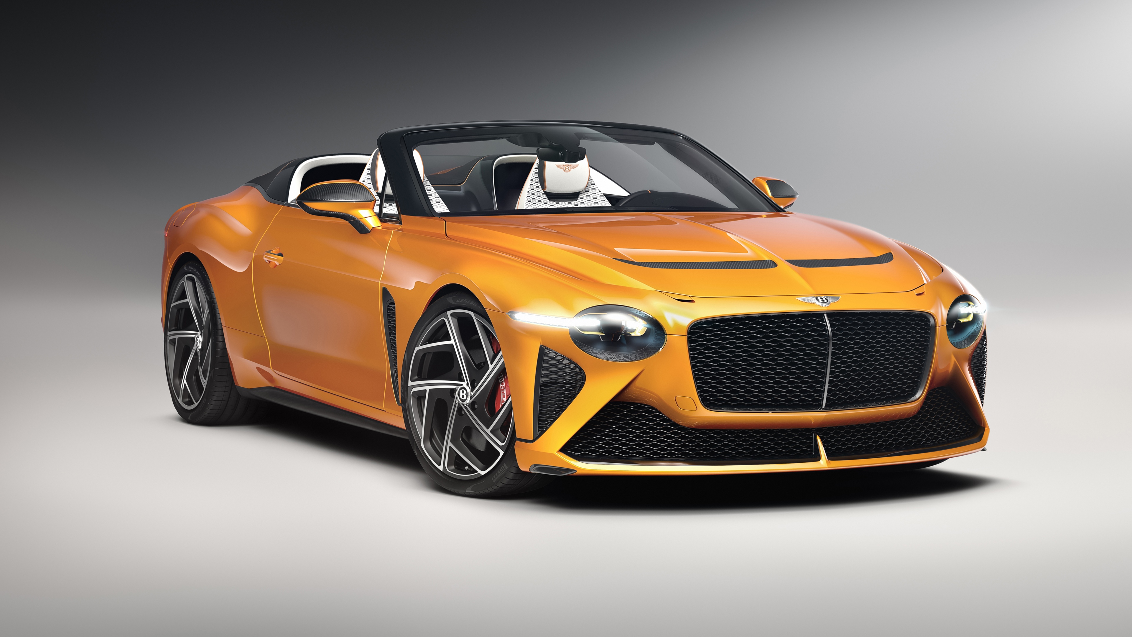 A stunning orange Bentley Mulliner Bacalar luxury convertible parked in a scenic setting.