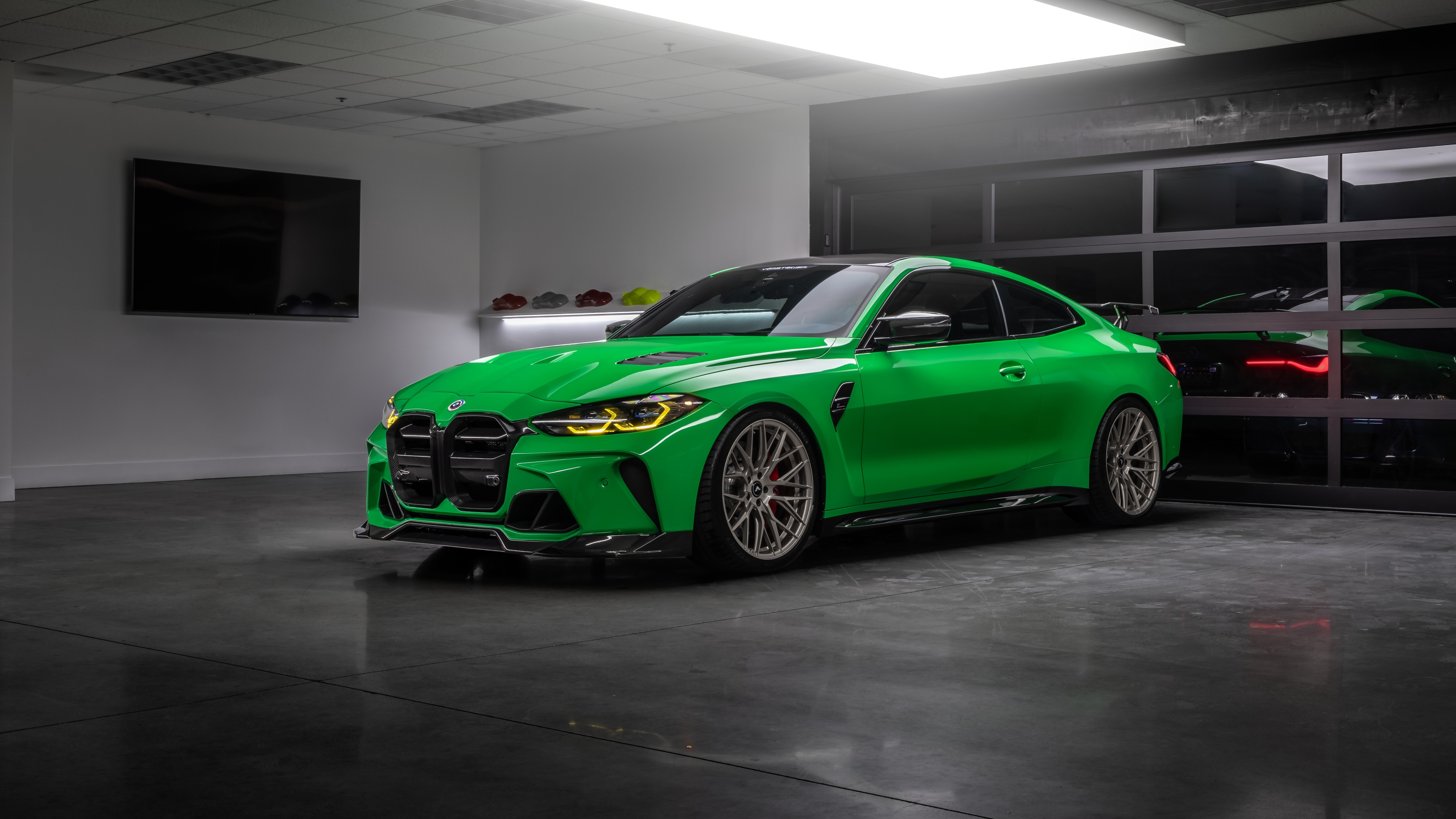 A modified green BMW M4 with Vorsteiner parts parked in a modern luxury garage.
