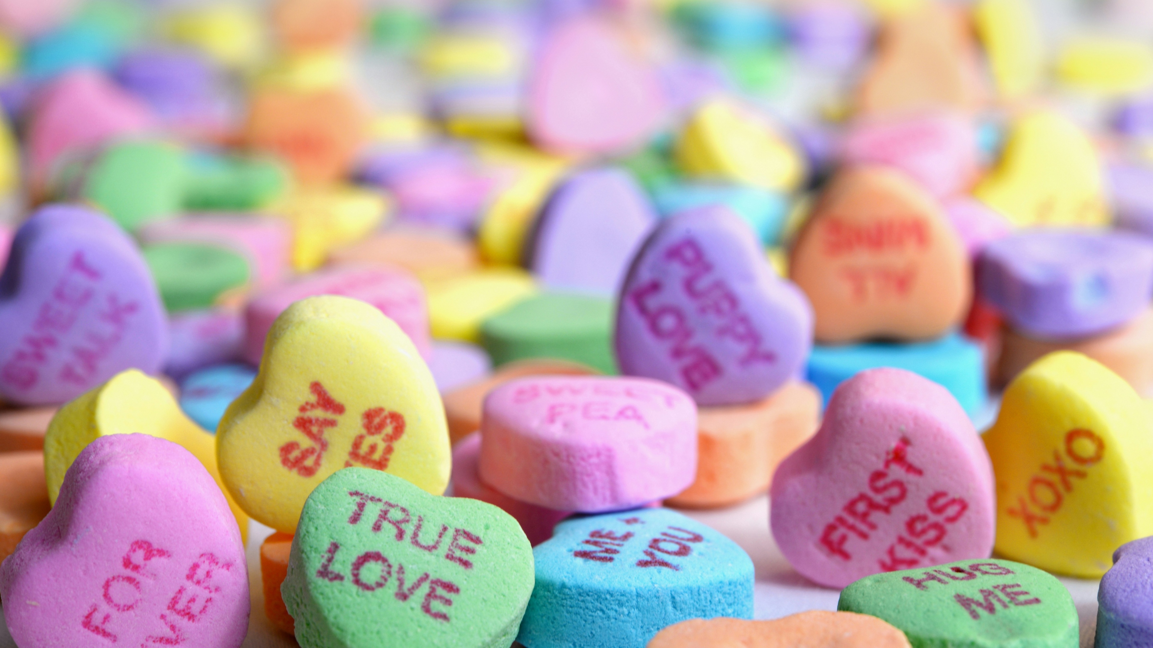 A romantic close-up featuring a first kiss surrounded by colorful heart-shaped sugar candies and Valentine decorations.