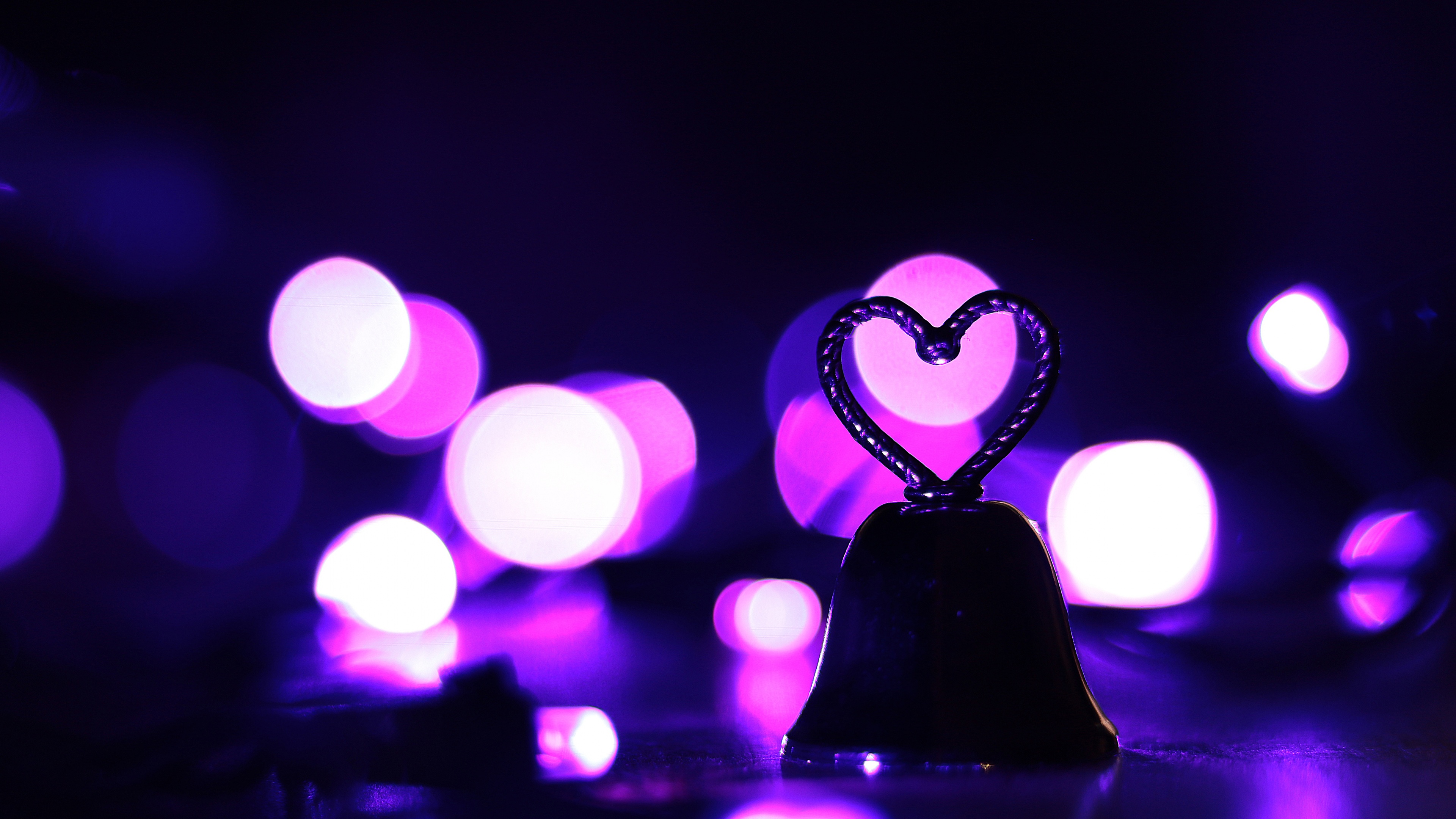 A glowing purple heart centered against a soft, dreamy violet bokeh light background.