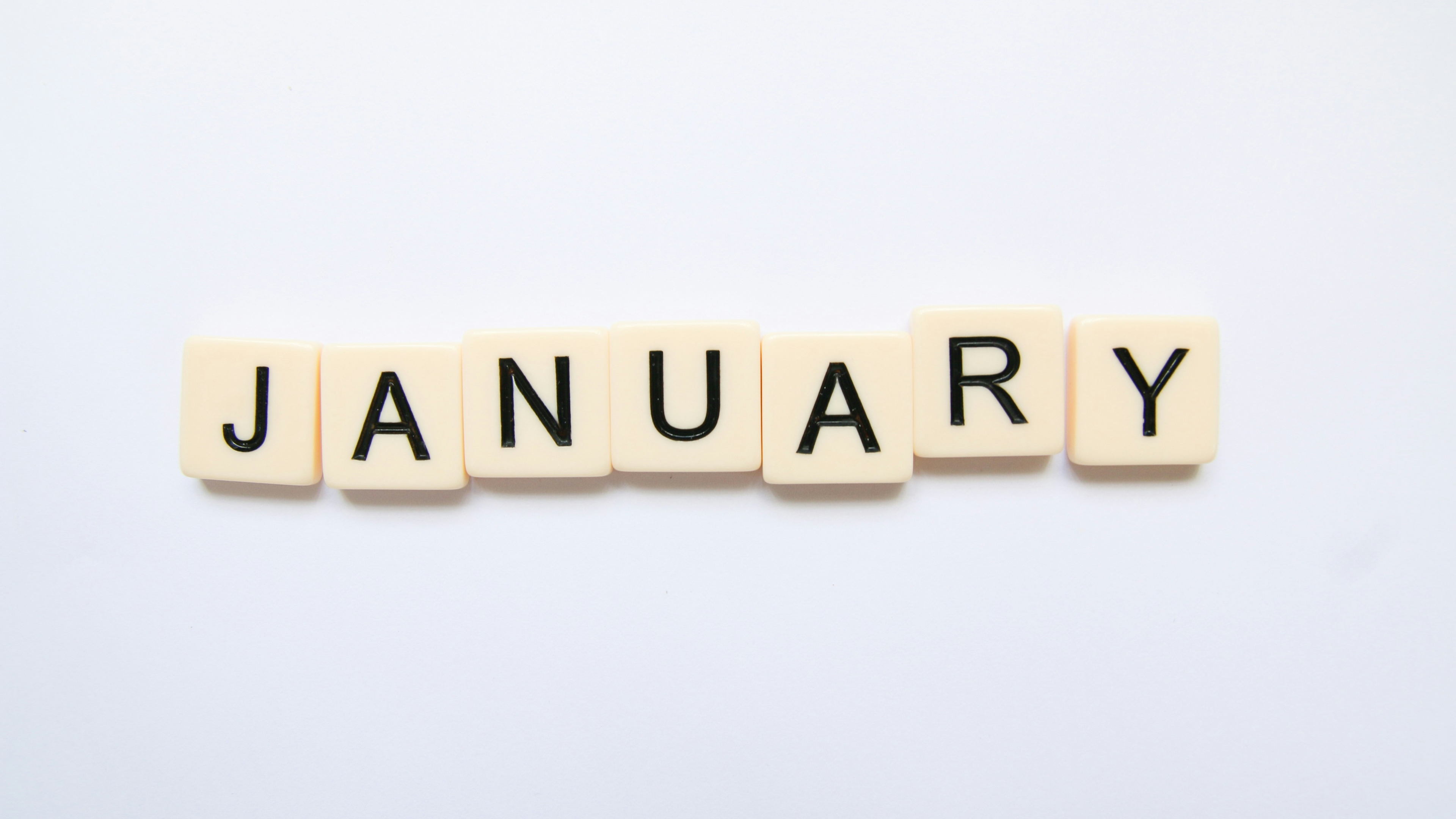 Scrabble tiles spelling the word January on a white background