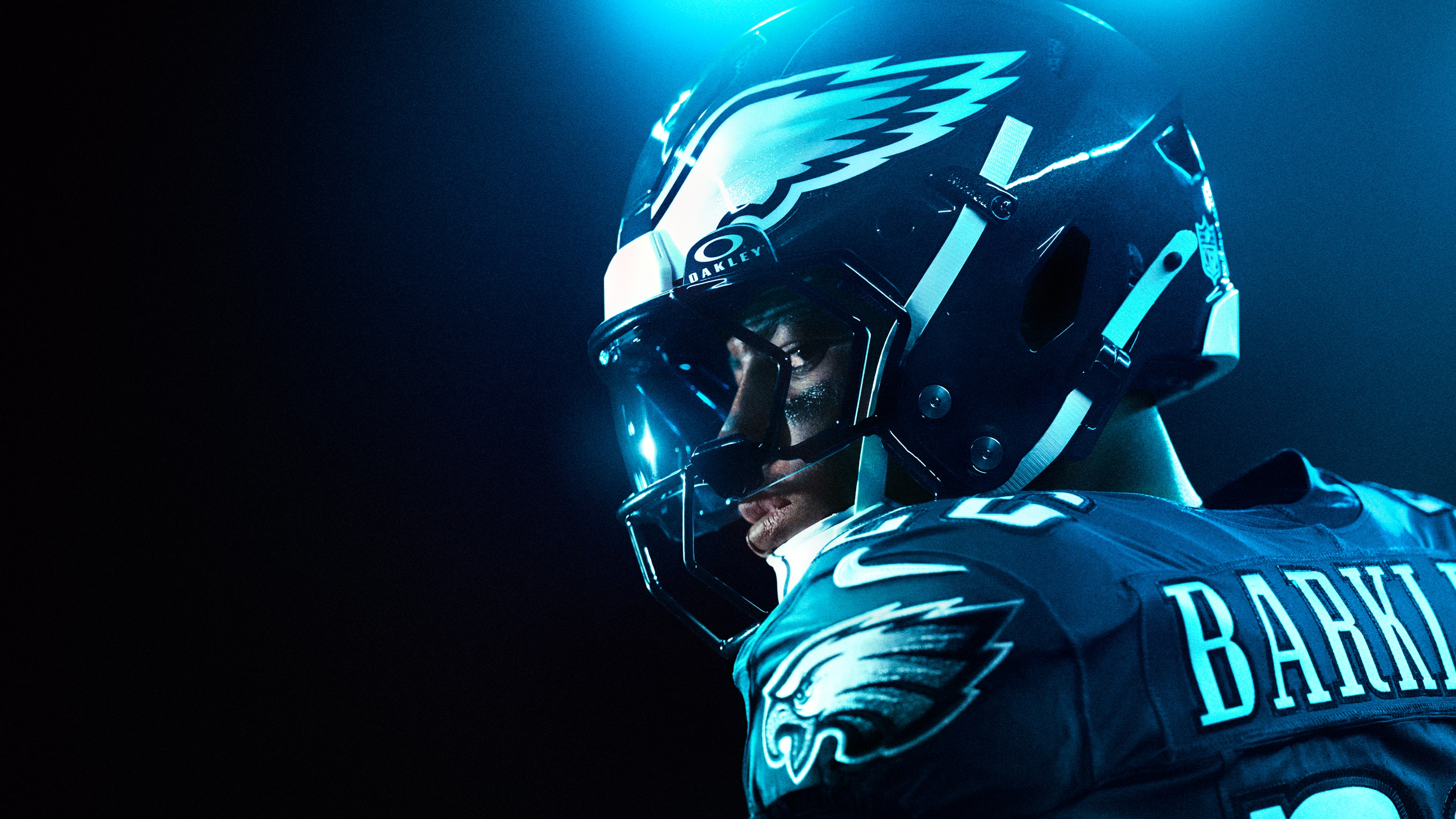 A dramatic cinematic shot of American football player Saquon Barkley illuminated by intense blue light, inspired by Madden NFL 26.