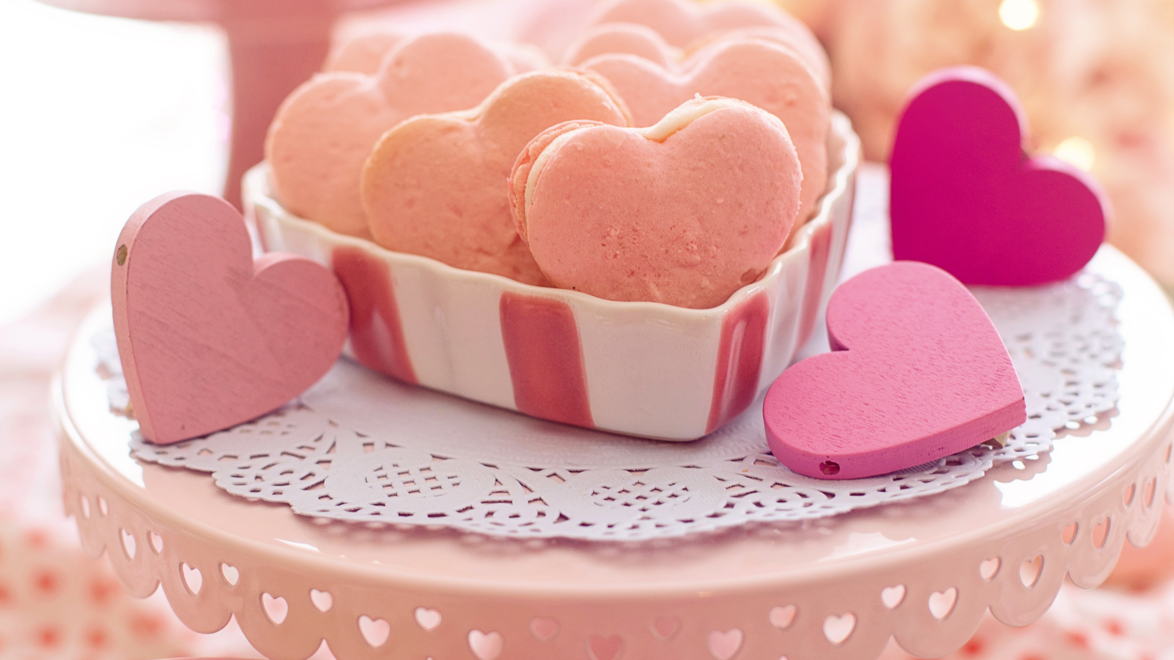 A collection of pink heart-shaped cookies with soft bokeh lighting and tiny heart accents in a romantic setting.