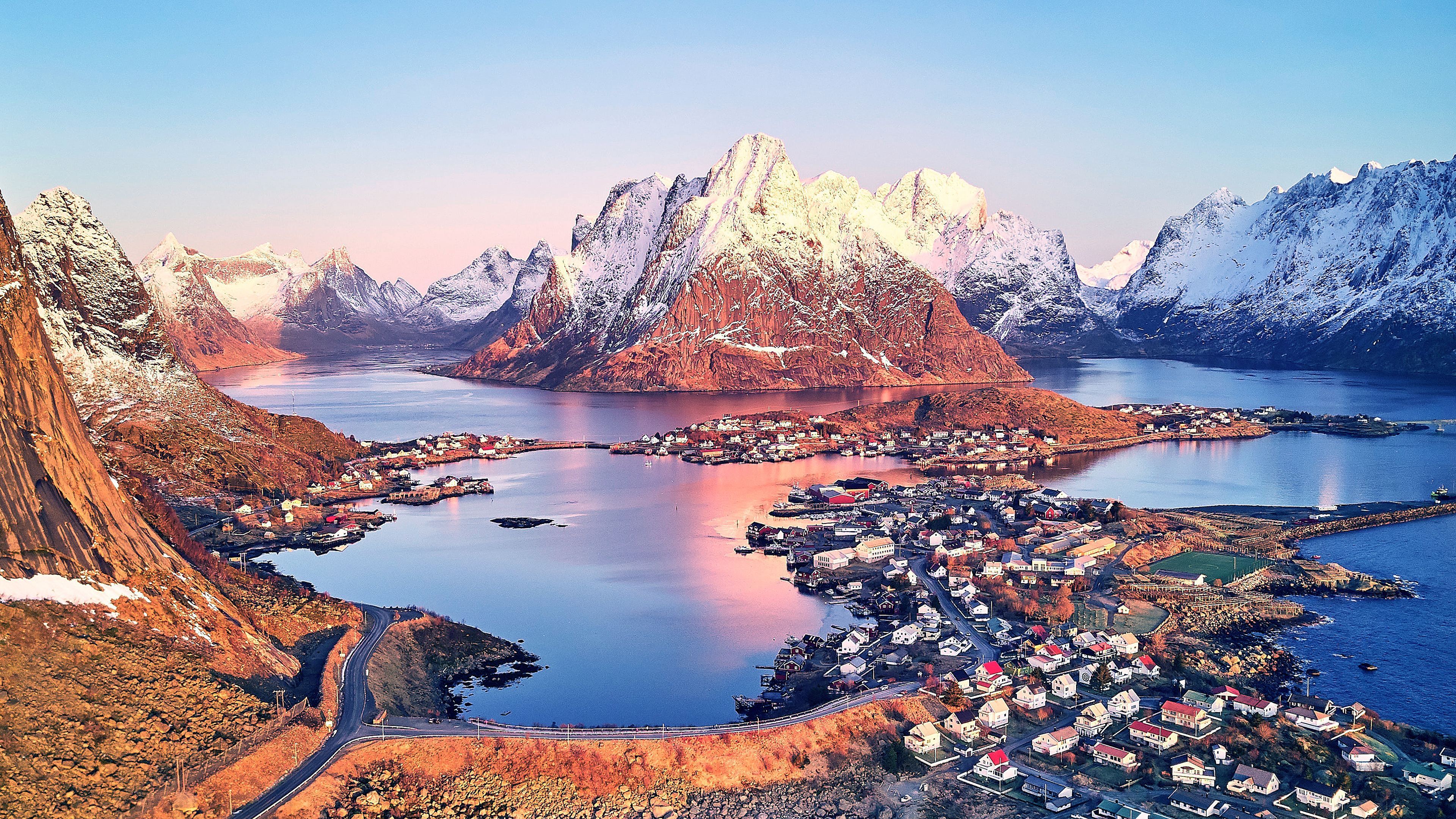 An aerial perspective of the scenic mountains and coastal waters surrounding Reine in the Lofoten Islands, Norway.