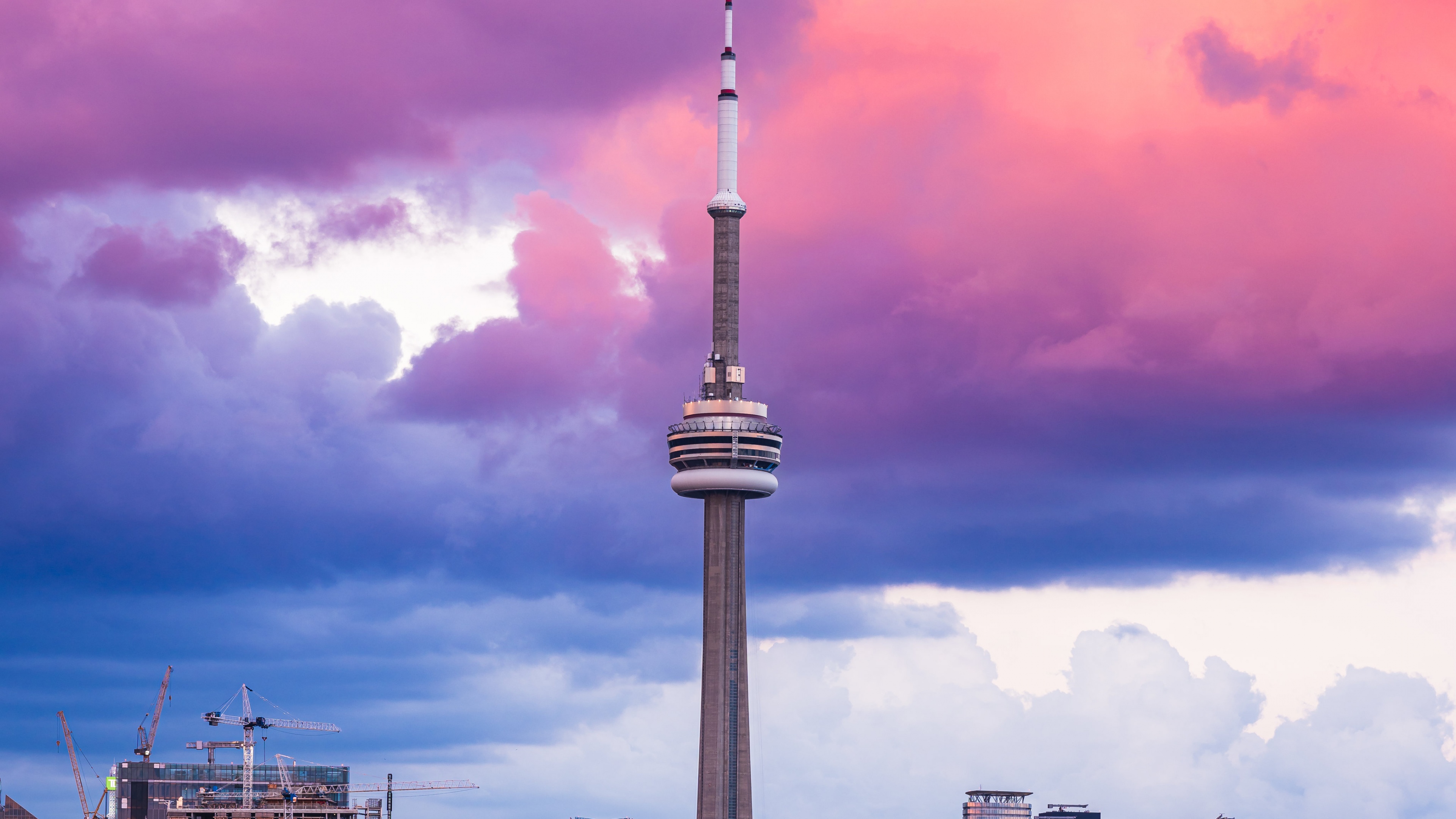 The CN Tower in Toronto, Ontario, under a sky filled with aesthetic pink clouds at sunset.