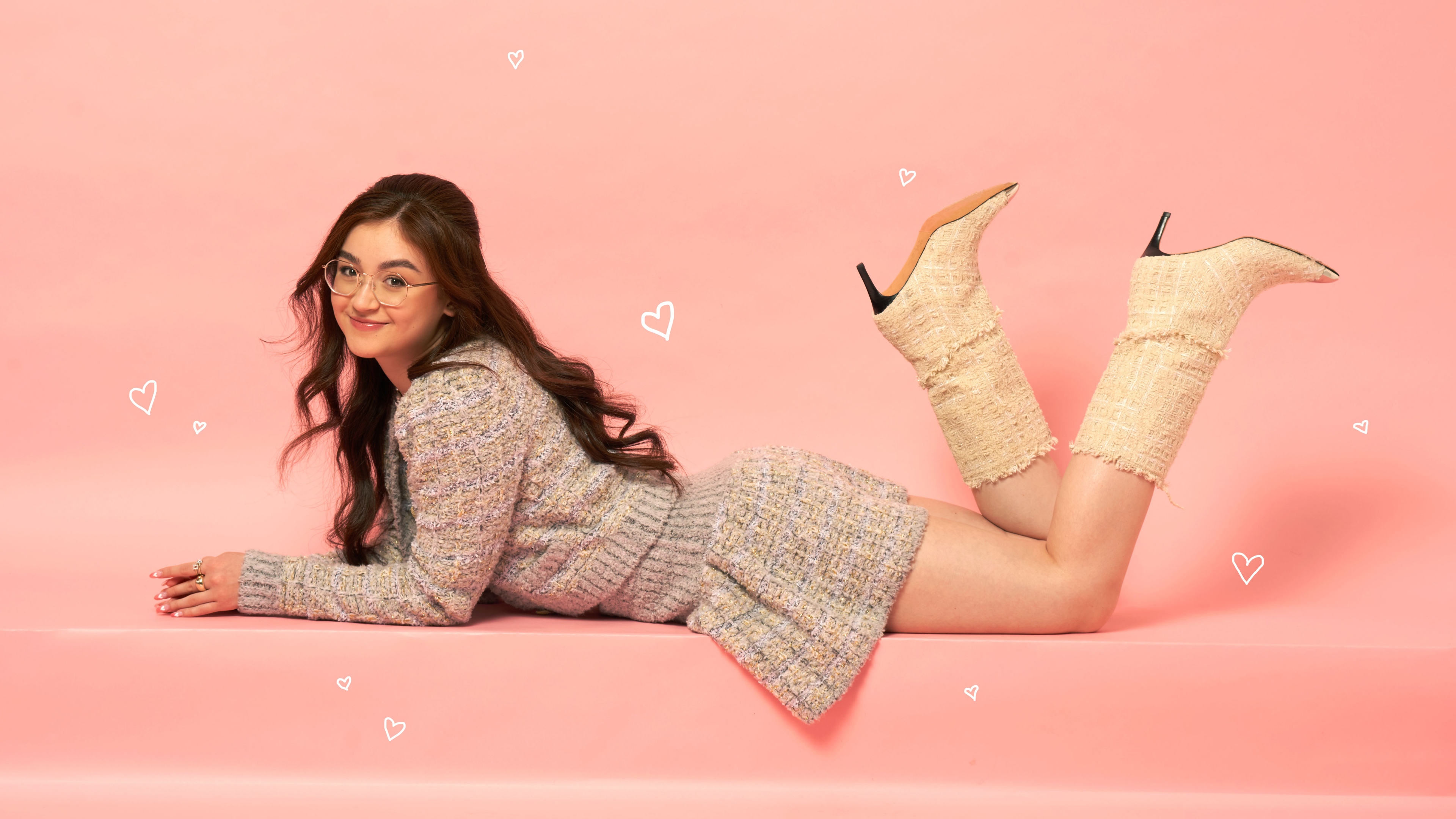 A beautiful portrait of Canadian actress Anna Cathcart against a peach-colored background with heart decorations.