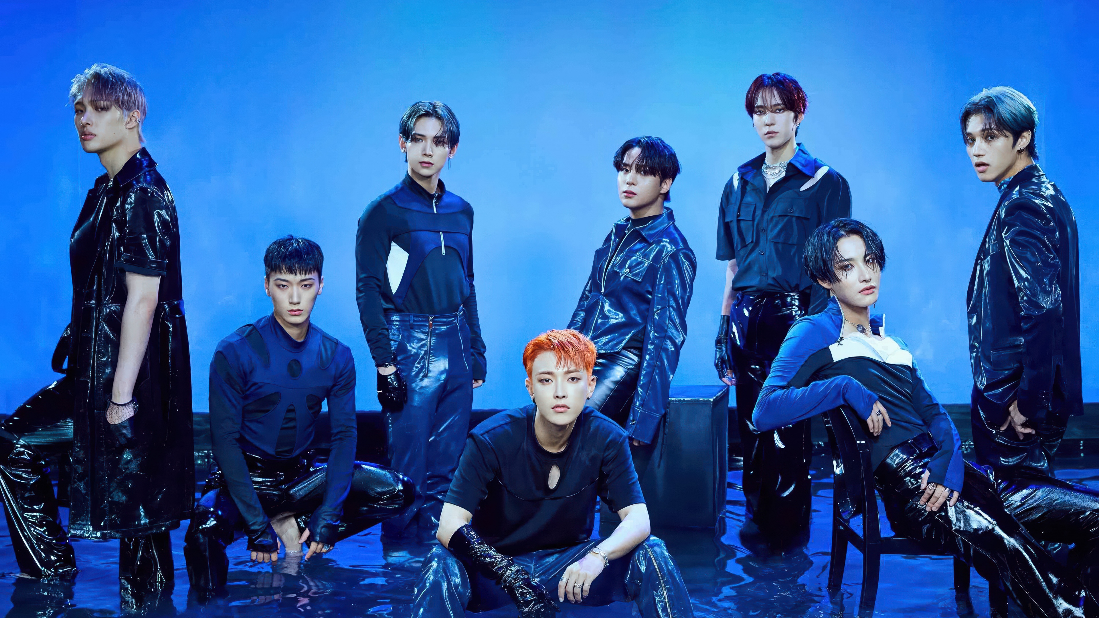 A high-resolution group portrait of ATEEZ members Hongjoong, Seonghwa, Yunho, Yeosang, San, Mingi, Wooyoung, and Jongho against a solid blue background.