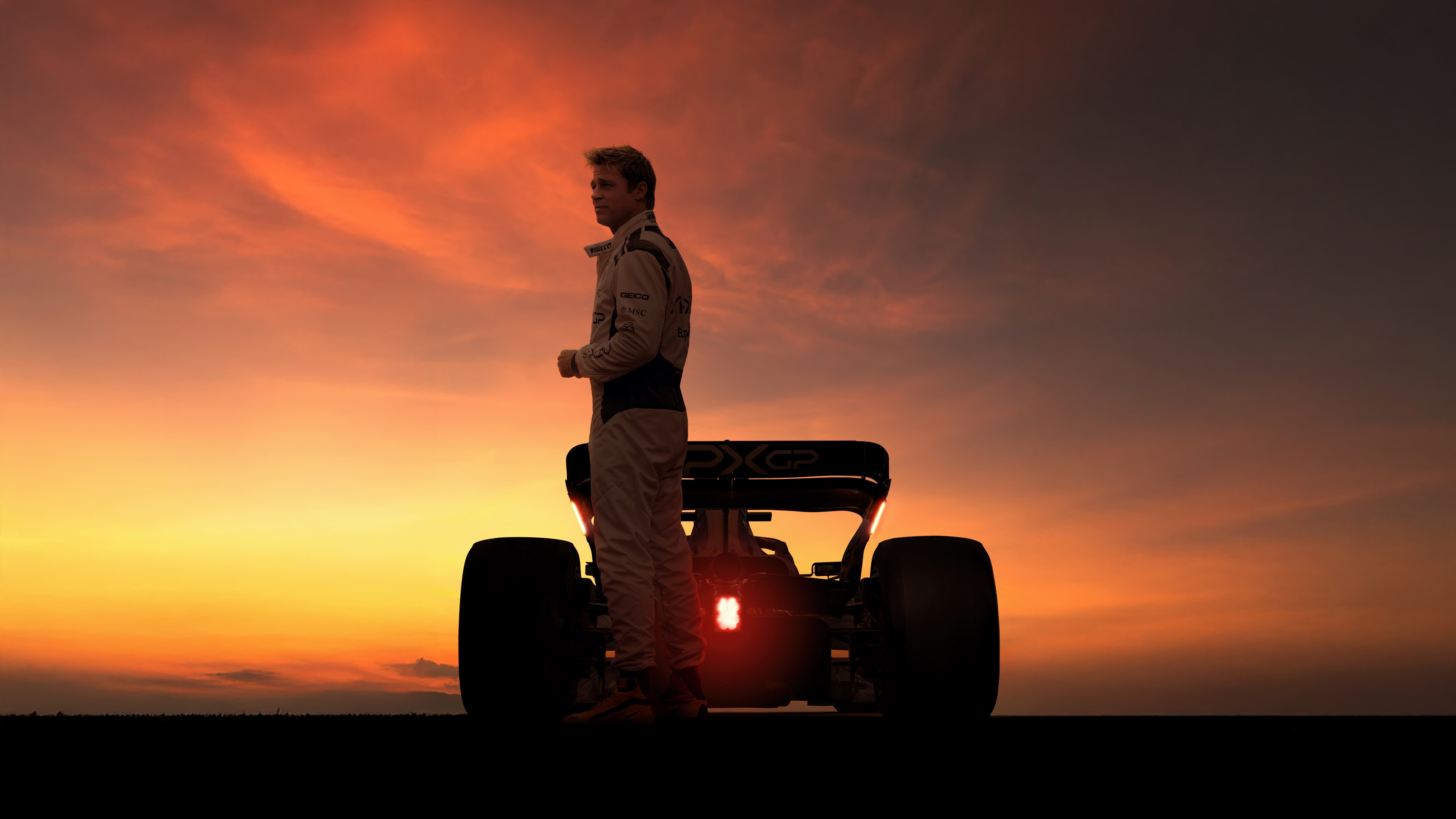 Brad Pitt posing against a dramatic sunset backdrop for the 2025 movie F1.