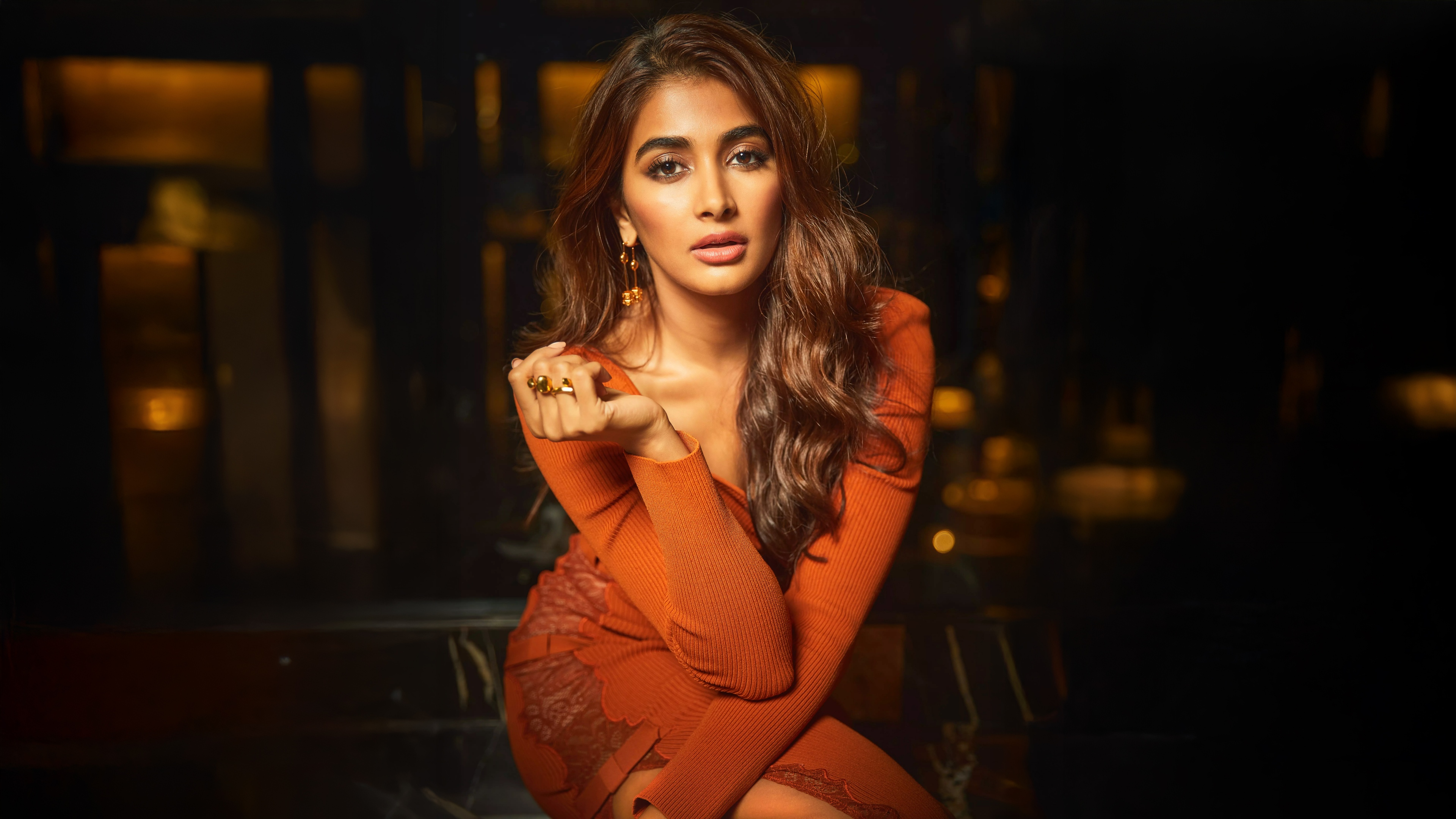A high-resolution, cinematic portrait of Indian actress Pooja Hegde featuring vibrant orange tones against a moody dark background.
