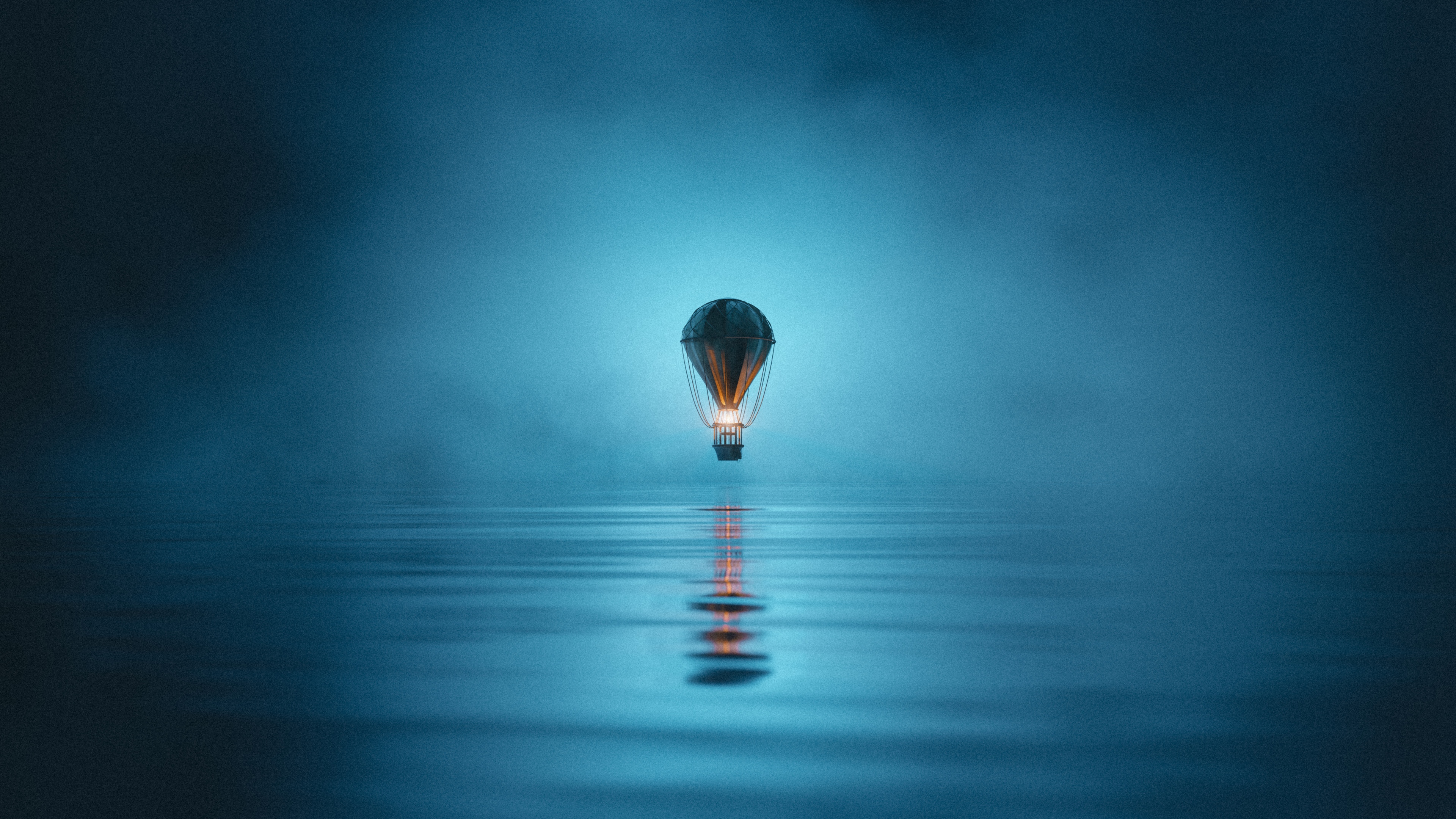 A hot air balloon floating in a misty and foggy night sky with reflections on a still water surface.