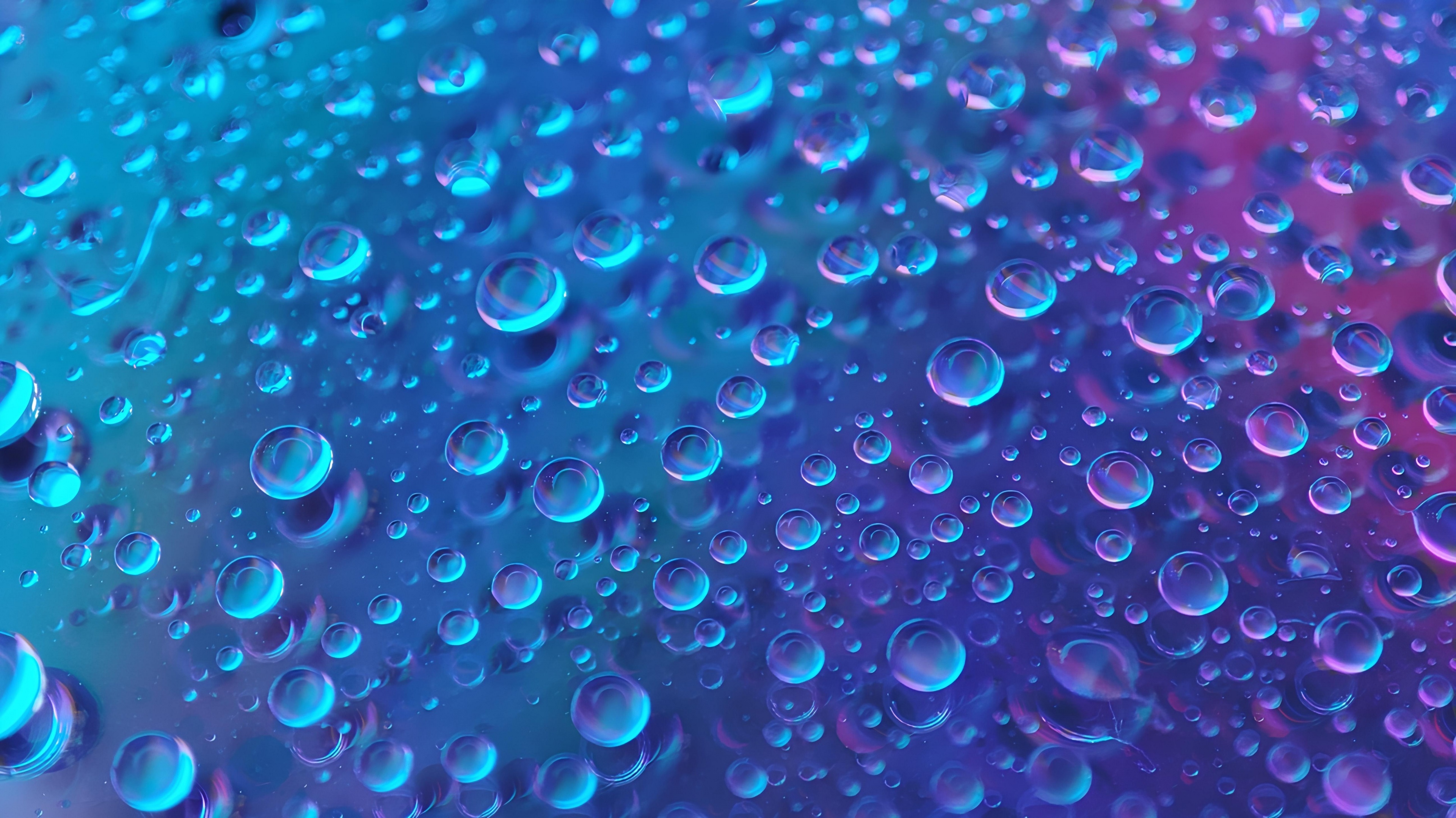Close-up macro photography of transparent rain droplets against a deep blue aesthetic background.