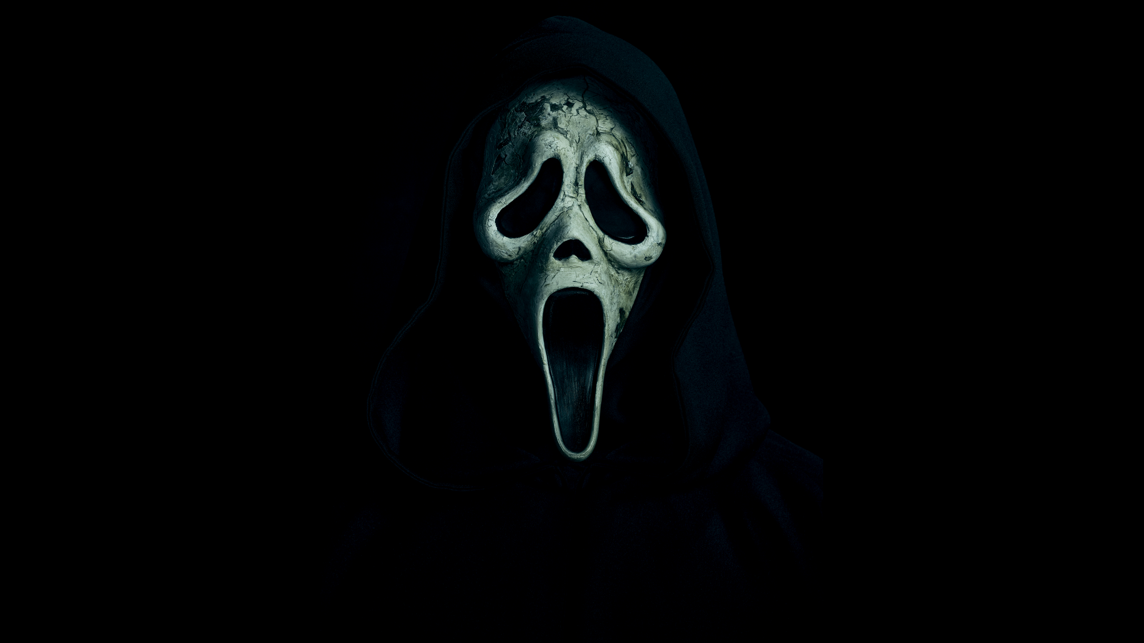 A high-contrast, close-up view of the Ghostface mask from the Scream movie franchise on a solid black background.