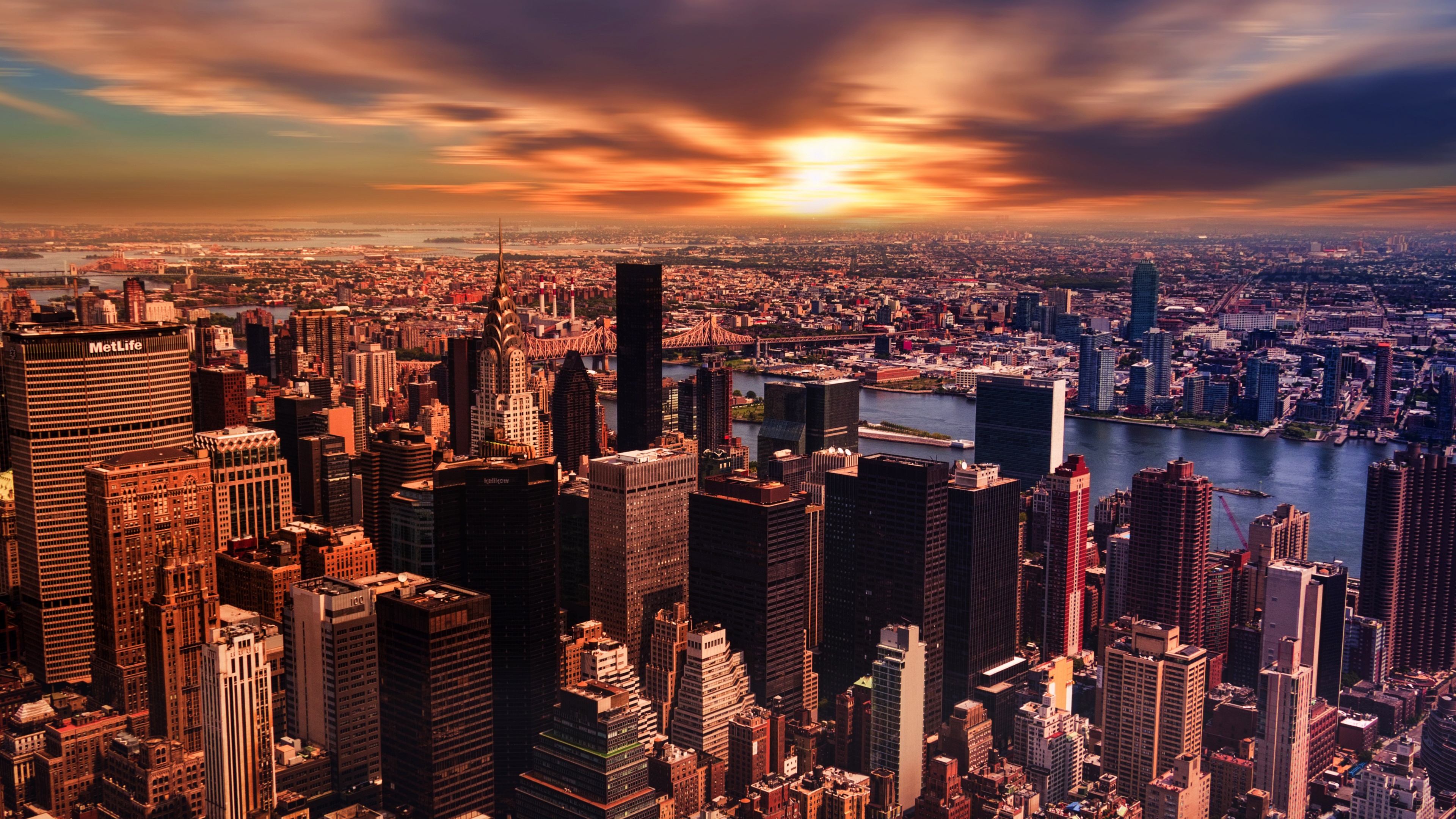 A dramatic New York City skyline at sunset with a cloudy, colorful sky.