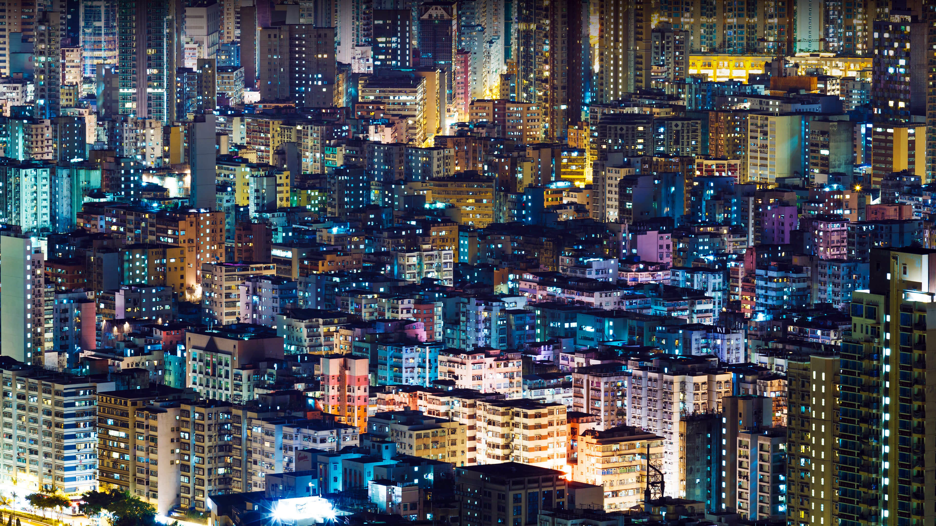 An illuminated cityscape with towering buildings and bright lights under a dark night sky.