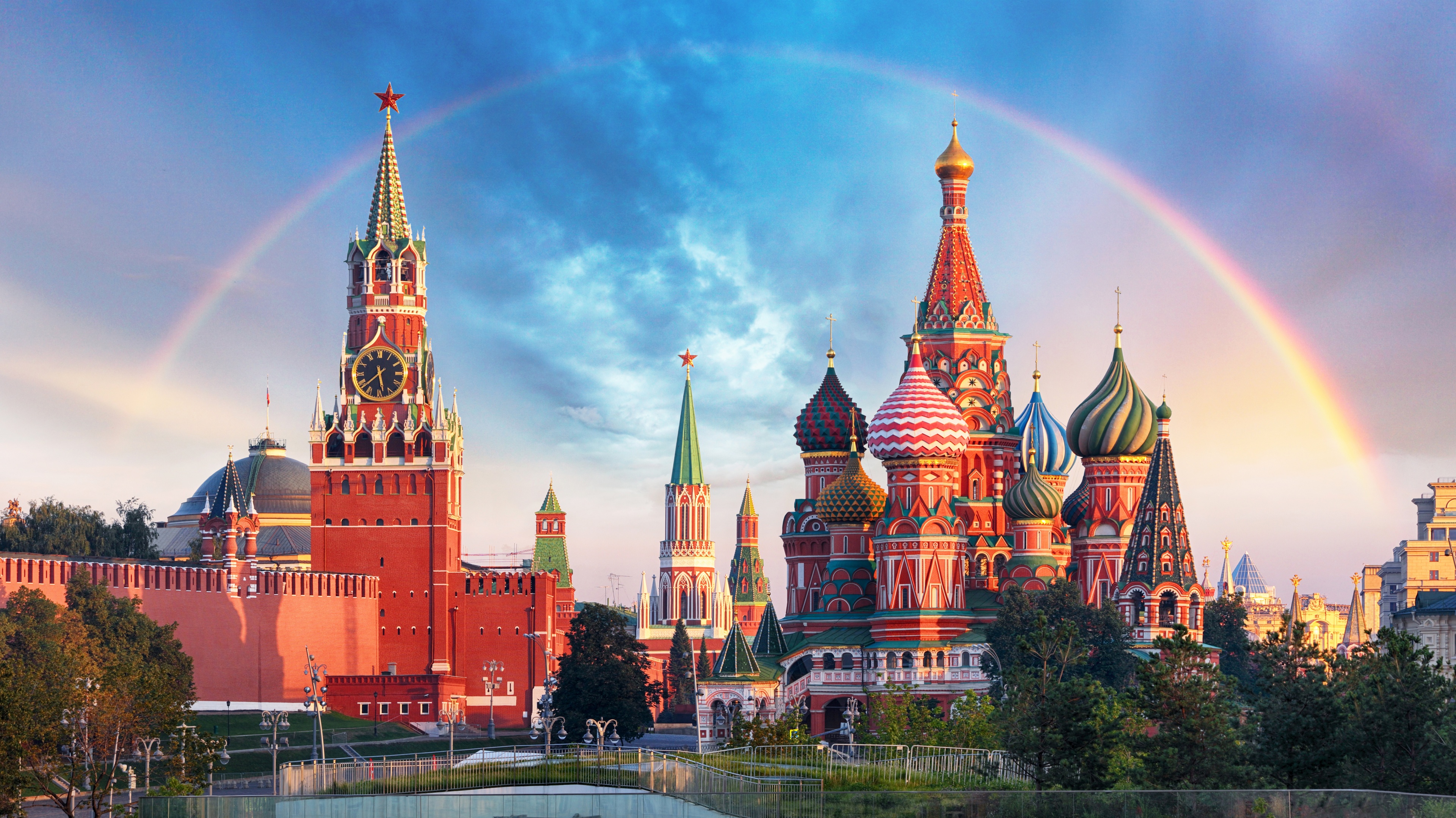 A panoramic view of the colorful onion domes of Saint Basil's Cathedral and historic stone architecture in Moscow, Russia.