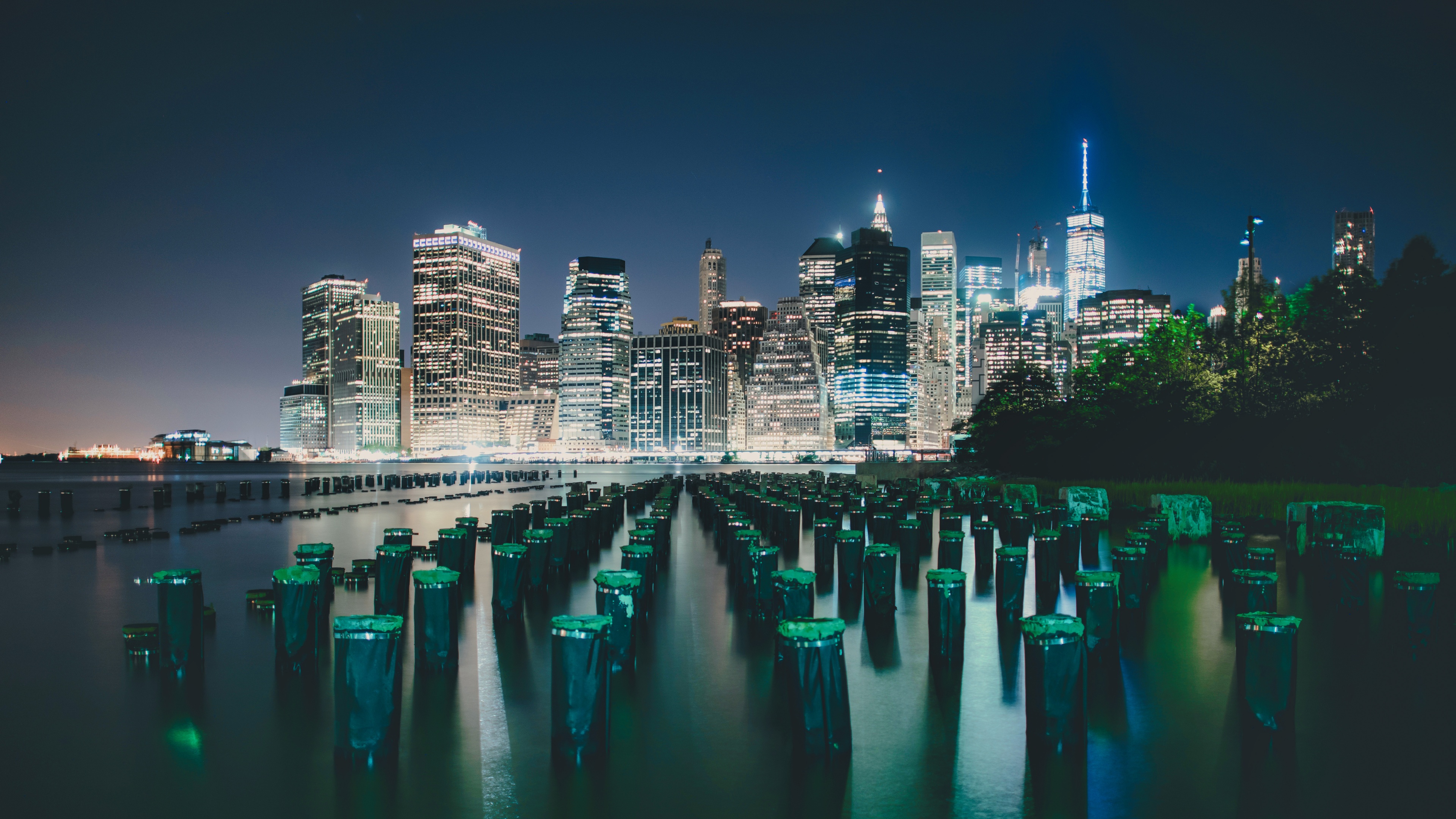 A high-resolution night view of the illuminated Manhattan skyline in New York City with bright city lights and skyscrapers.