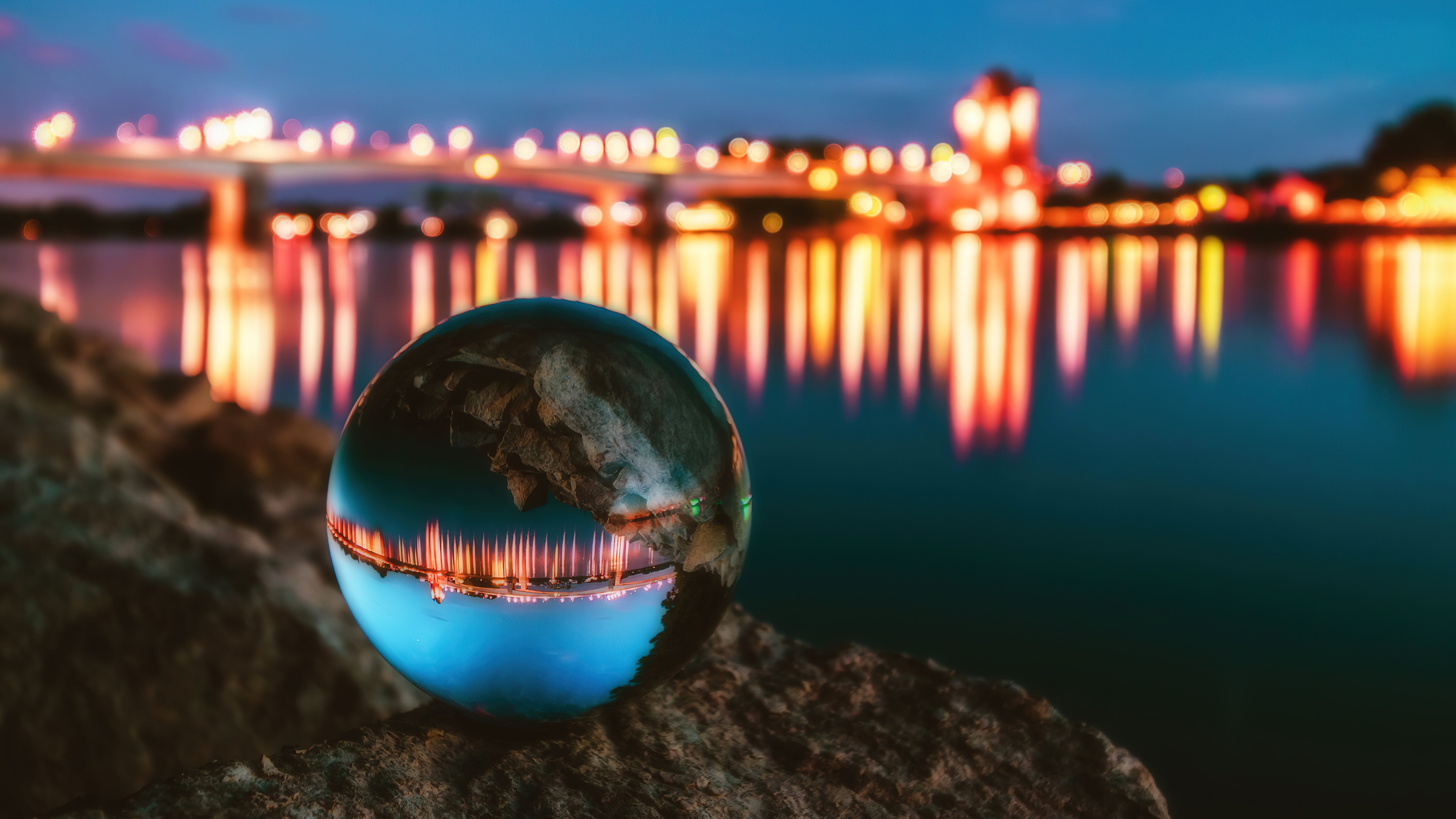 Macro shot of a crystal ball reflecting a brightly lit night cityscape with glowing neon lights and skyscrapers.