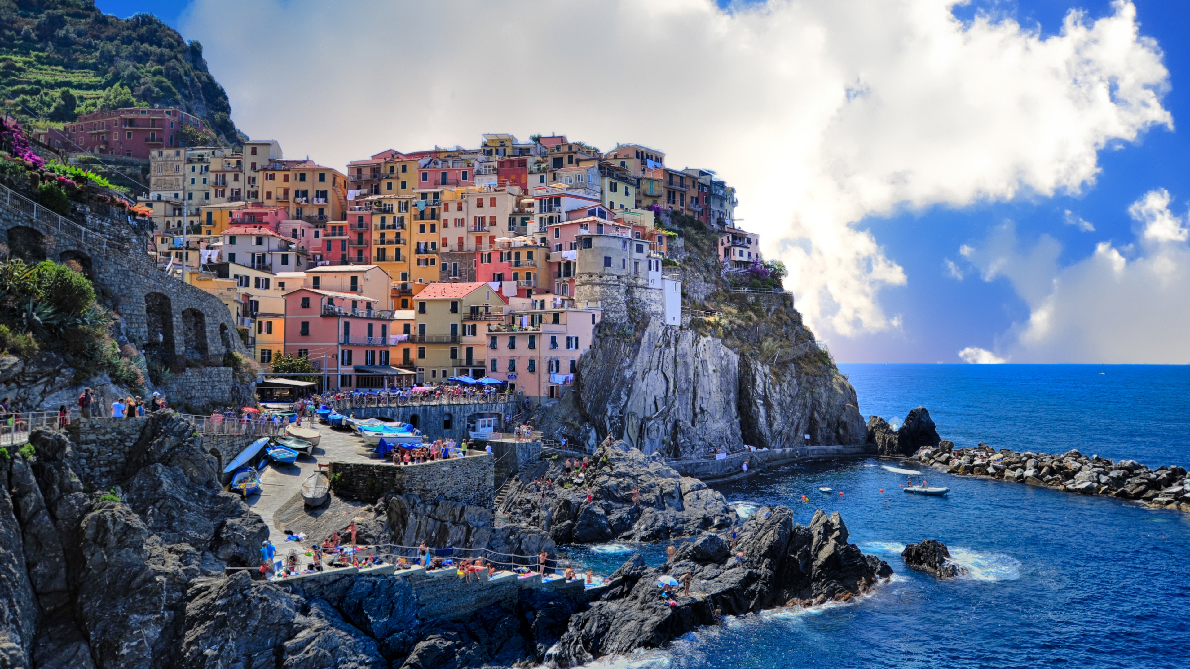 A panoramic view of the colorful seaside village of Manarola in Cinque Terre, Italy, under bright daylight.