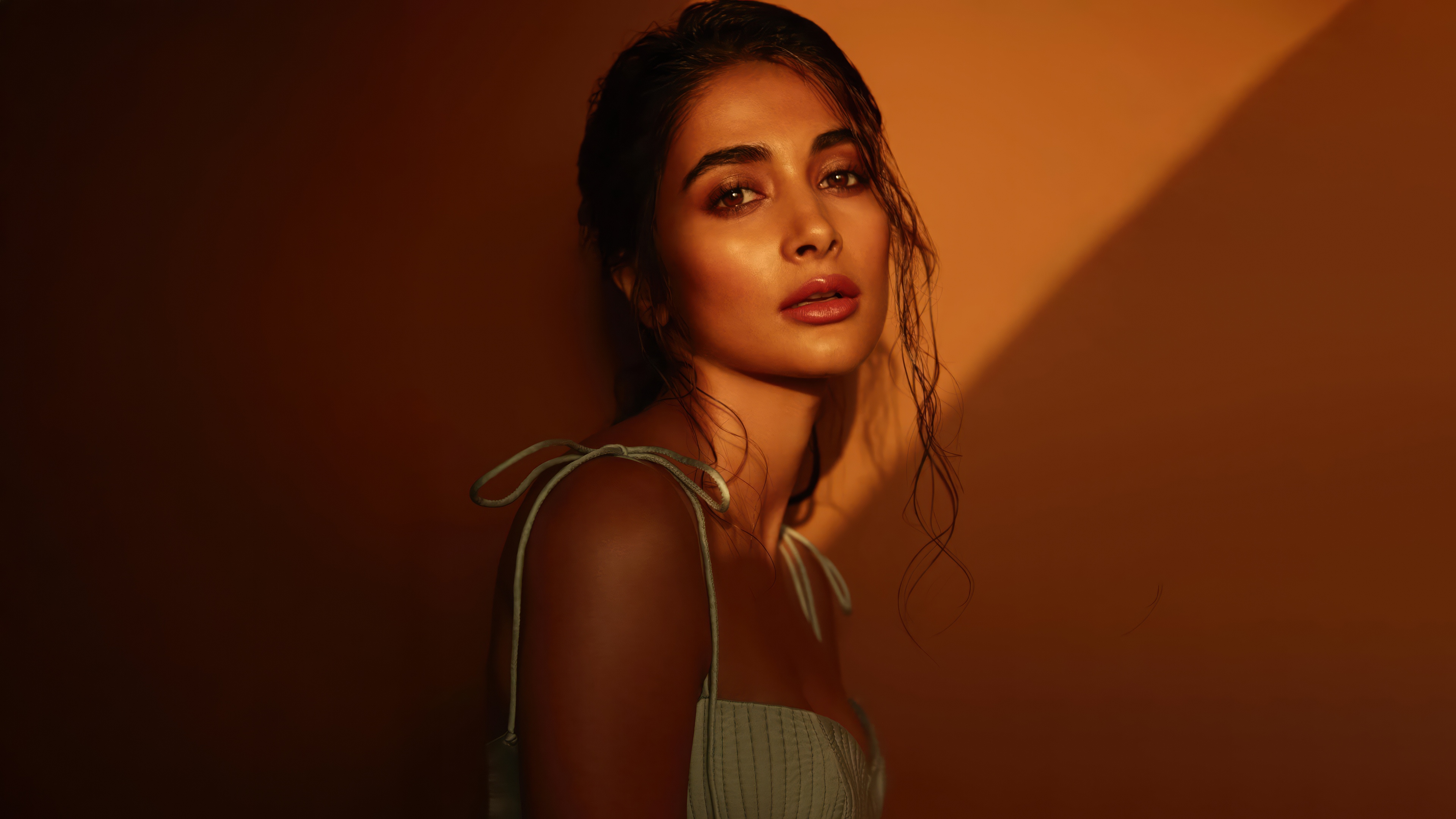 A cinematic portrait of Indian actress Pooja Hegde illuminated by the warm, golden light of a sunset.
