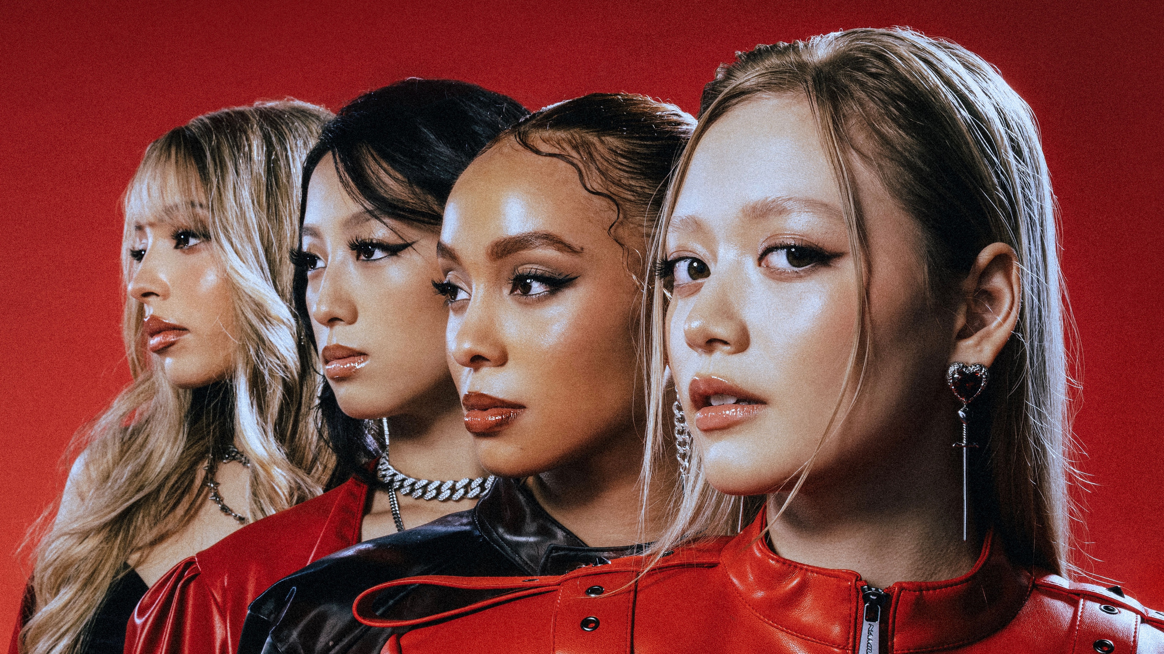 A group of American female singers posing together in front of a bold red studio background.