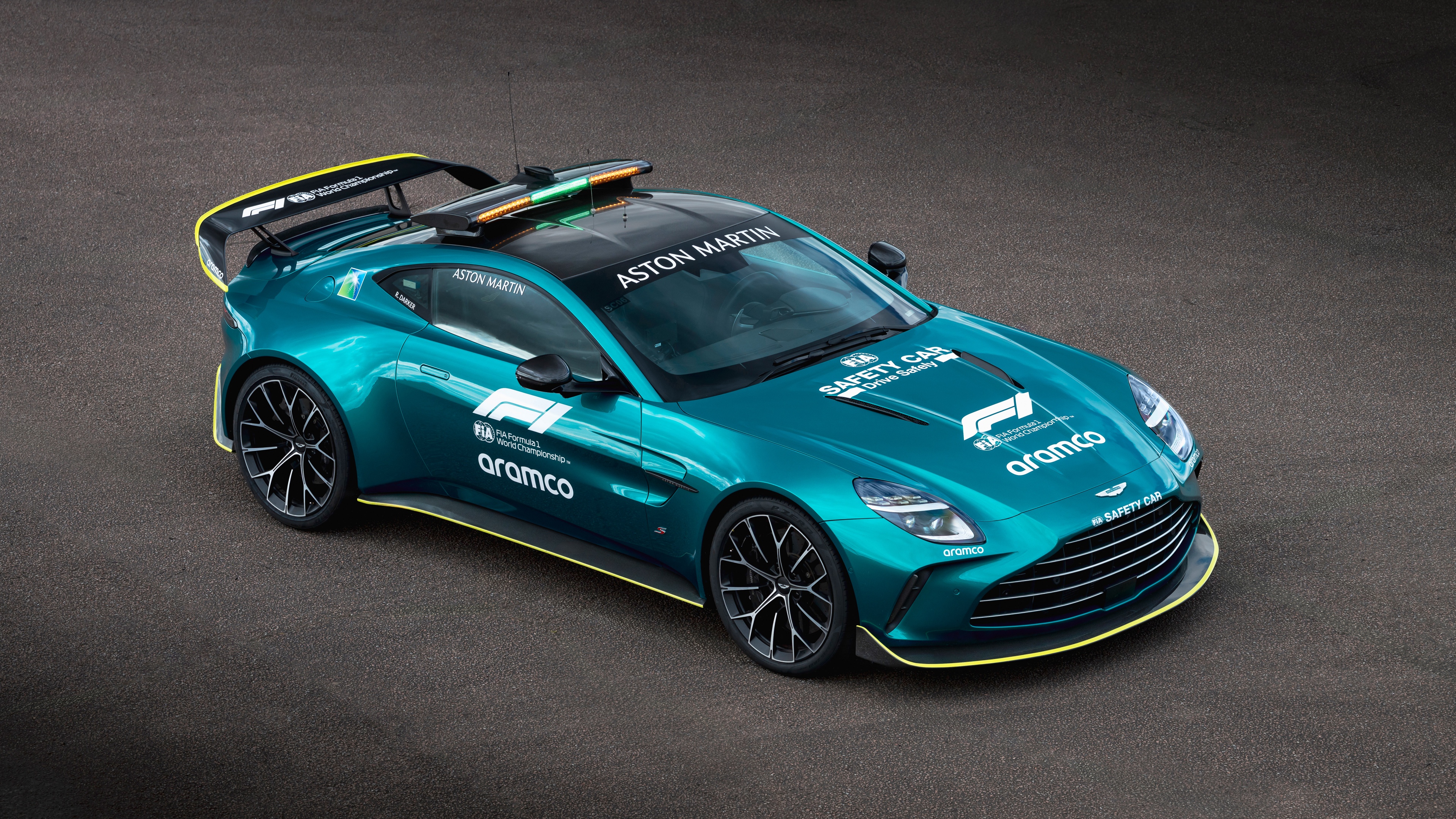 A high-performance Aston Martin Vantage S configured as an F1 Safety Car on a racing track.