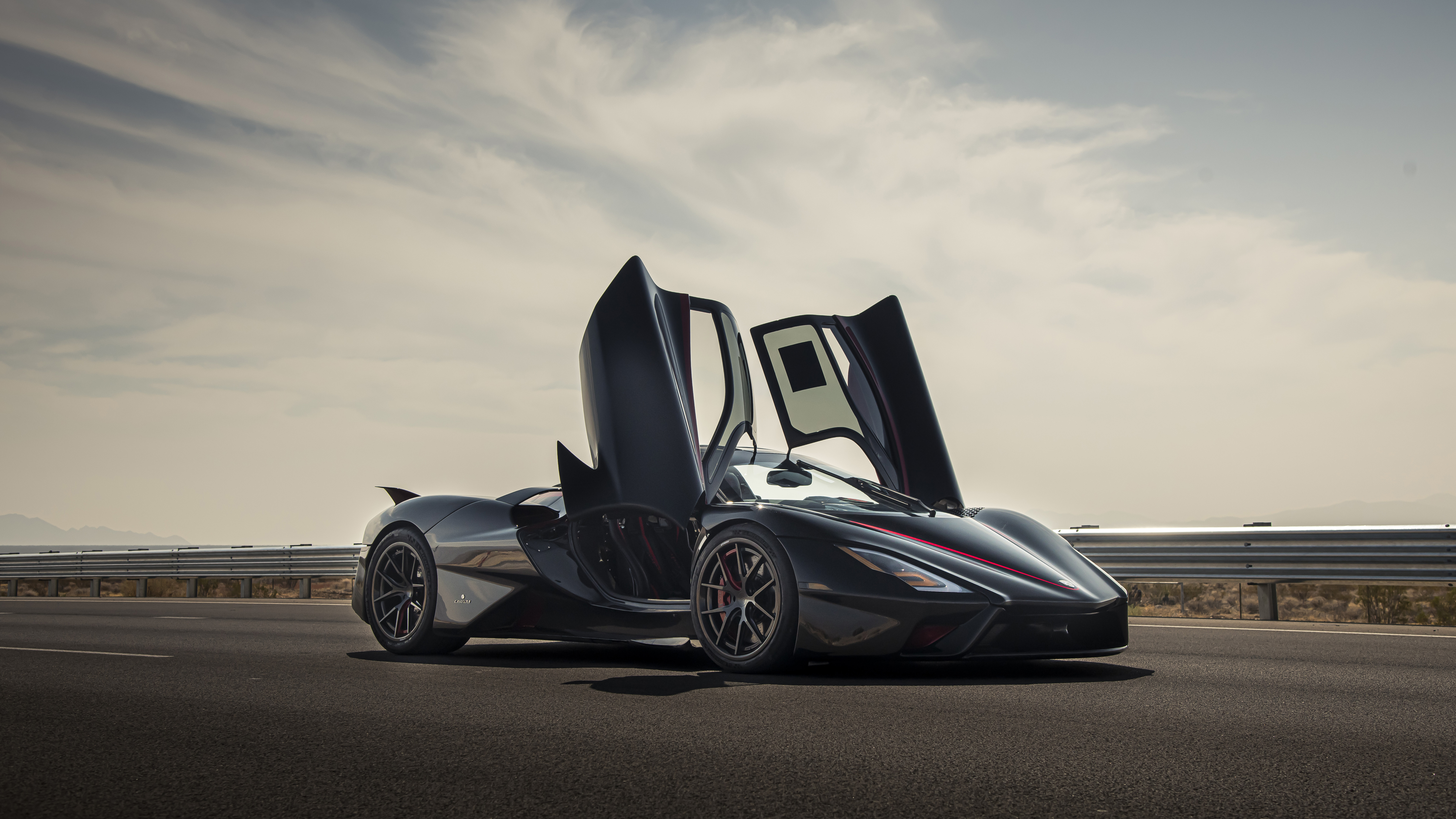 Un primo piano di una moderna e slanciata hypercar SSC Tuatara di colore nero, che ne mette in risalto la carrozzeria aerodinamica.