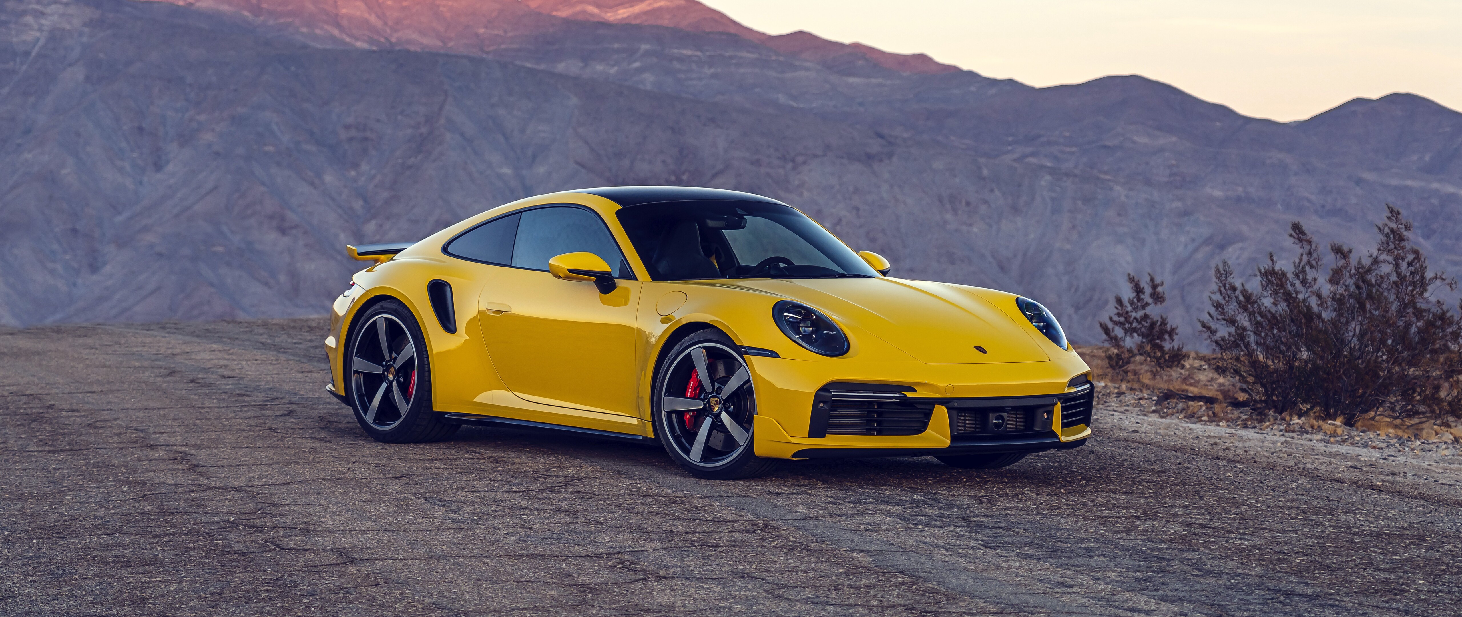 Una sportiva Porsche 911 Turbo di un giallo brillante, caratterizzata da un design elegante e aerodinamico.