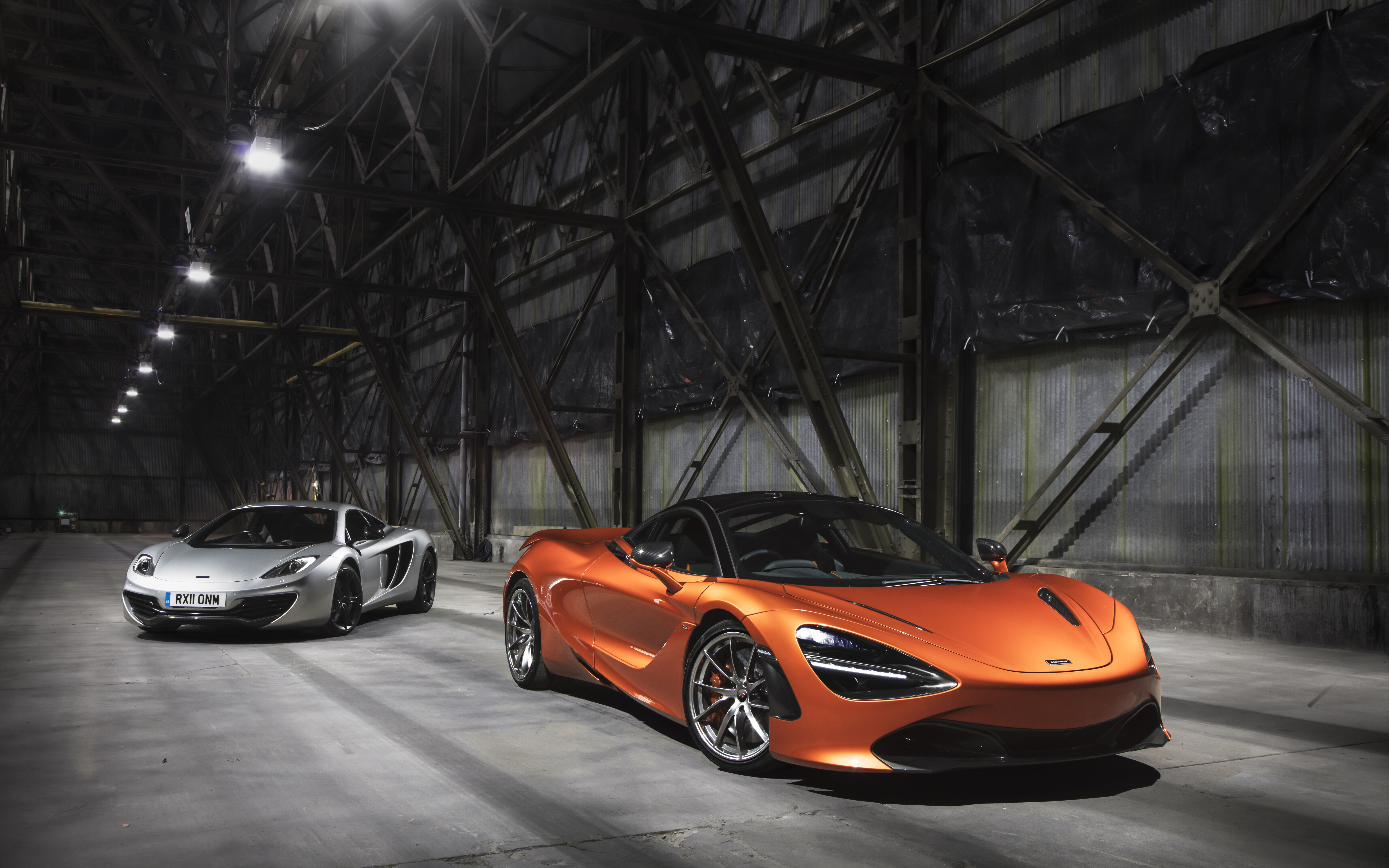 Two McLaren 720S supercars, one in metallic silver and one in bright orange, positioned side by side.