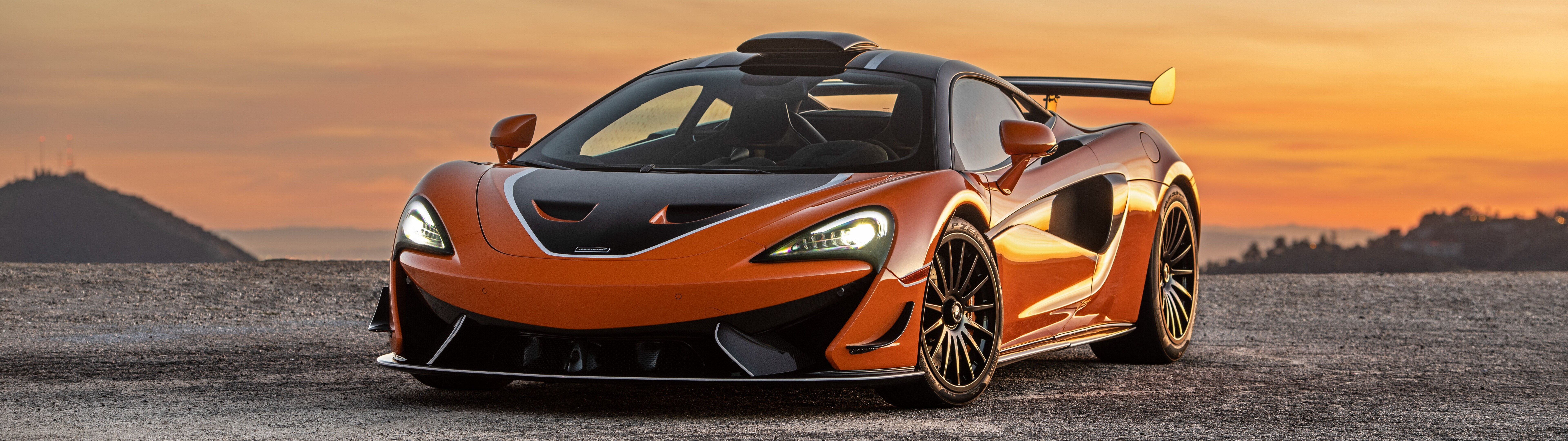 A high-performance McLaren 620R supercar in a striking vibrant orange color.