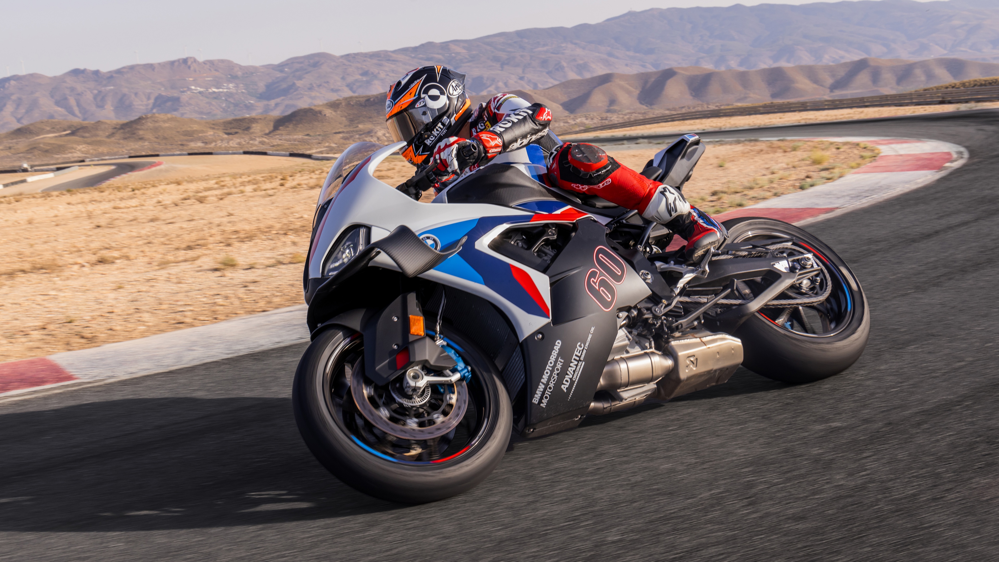 A 2024 BMW M 1000 RR motorcycle speeding along a professional racing circuit.