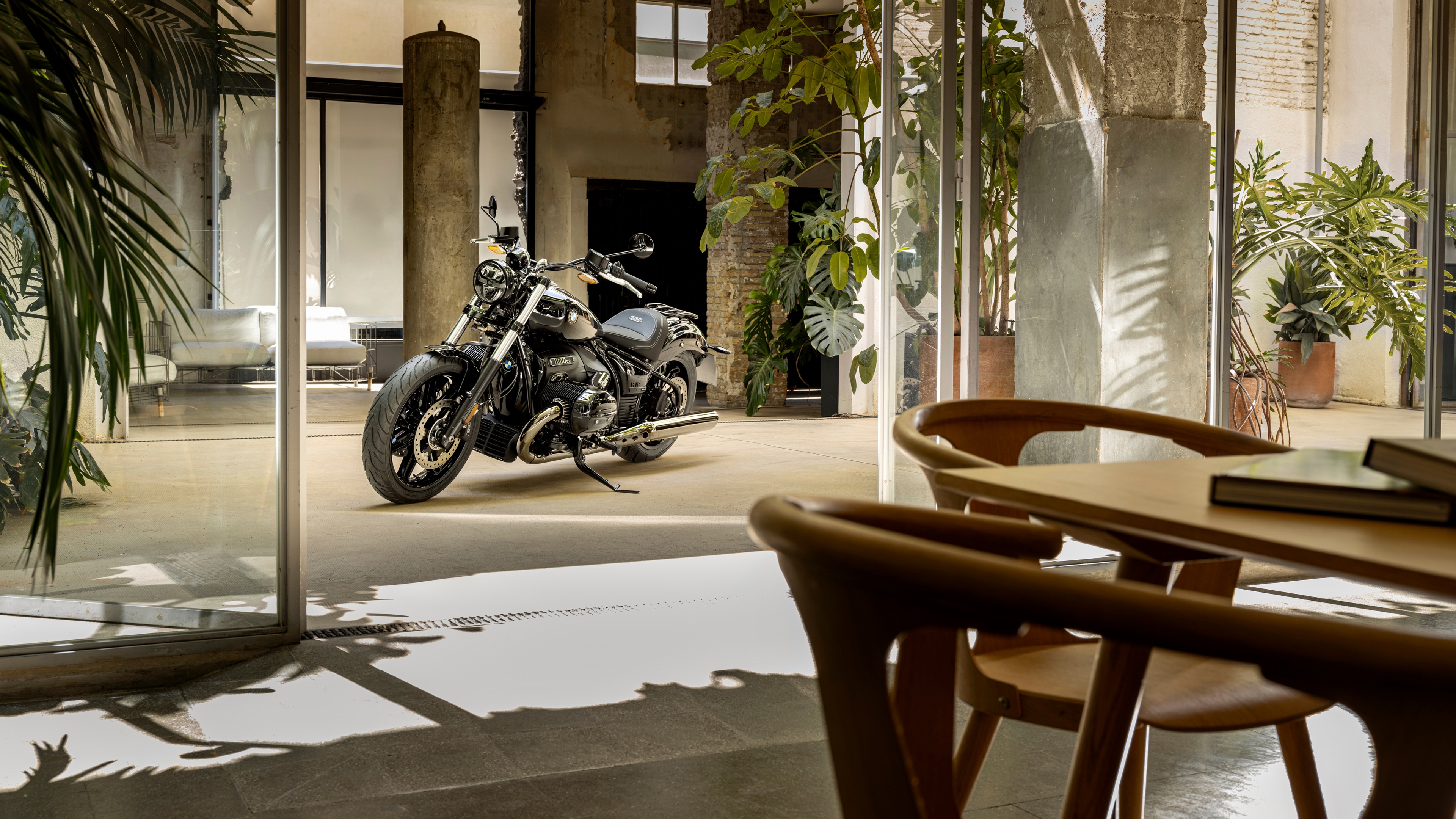 A high-resolution shot of a BMW R 18 cruiser motorcycle parked inside a contemporary minimalist showroom with luxury decor.