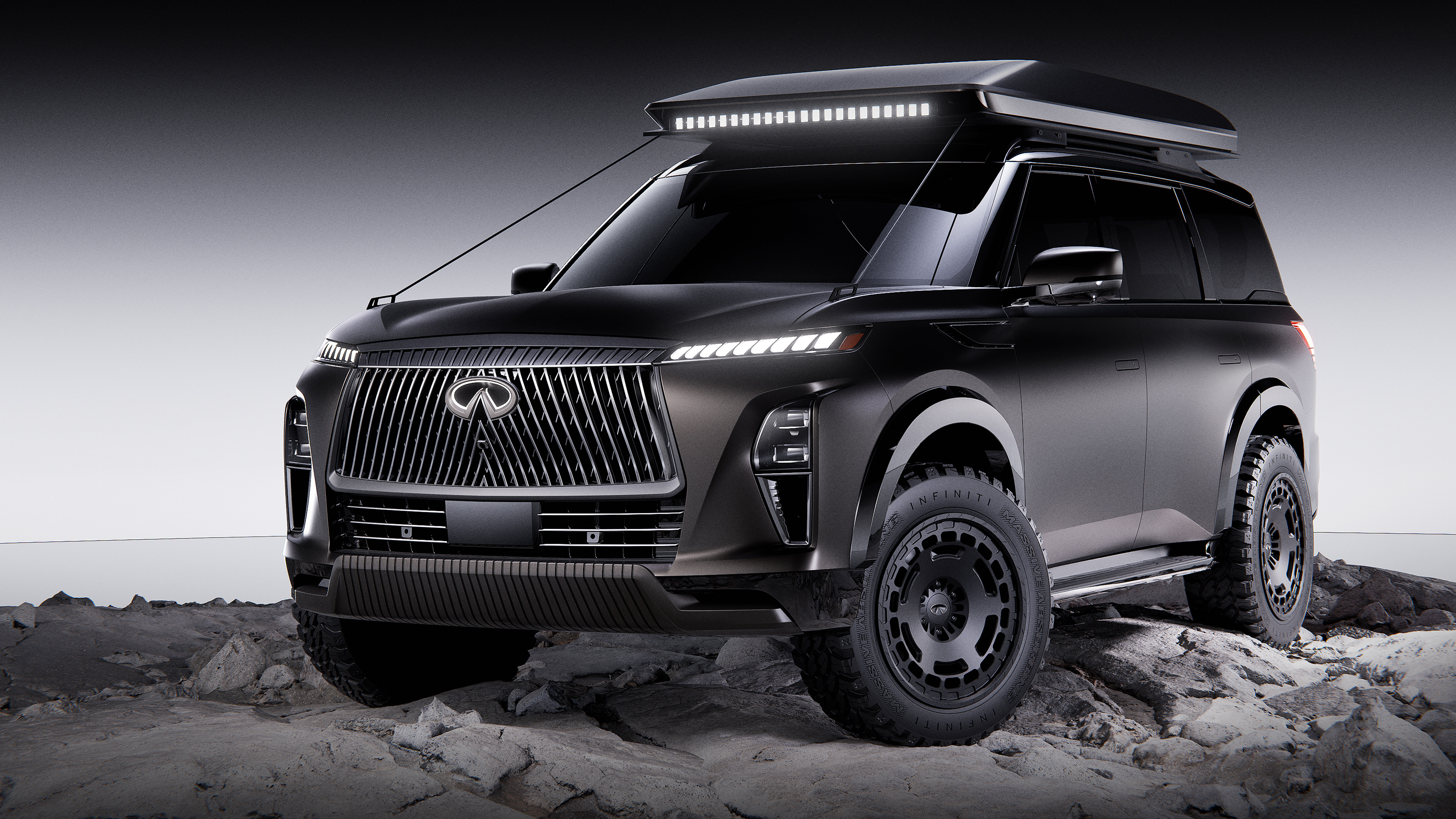 A high-contrast monochrome shot of a 2025 Infiniti QX80 against a dark background.