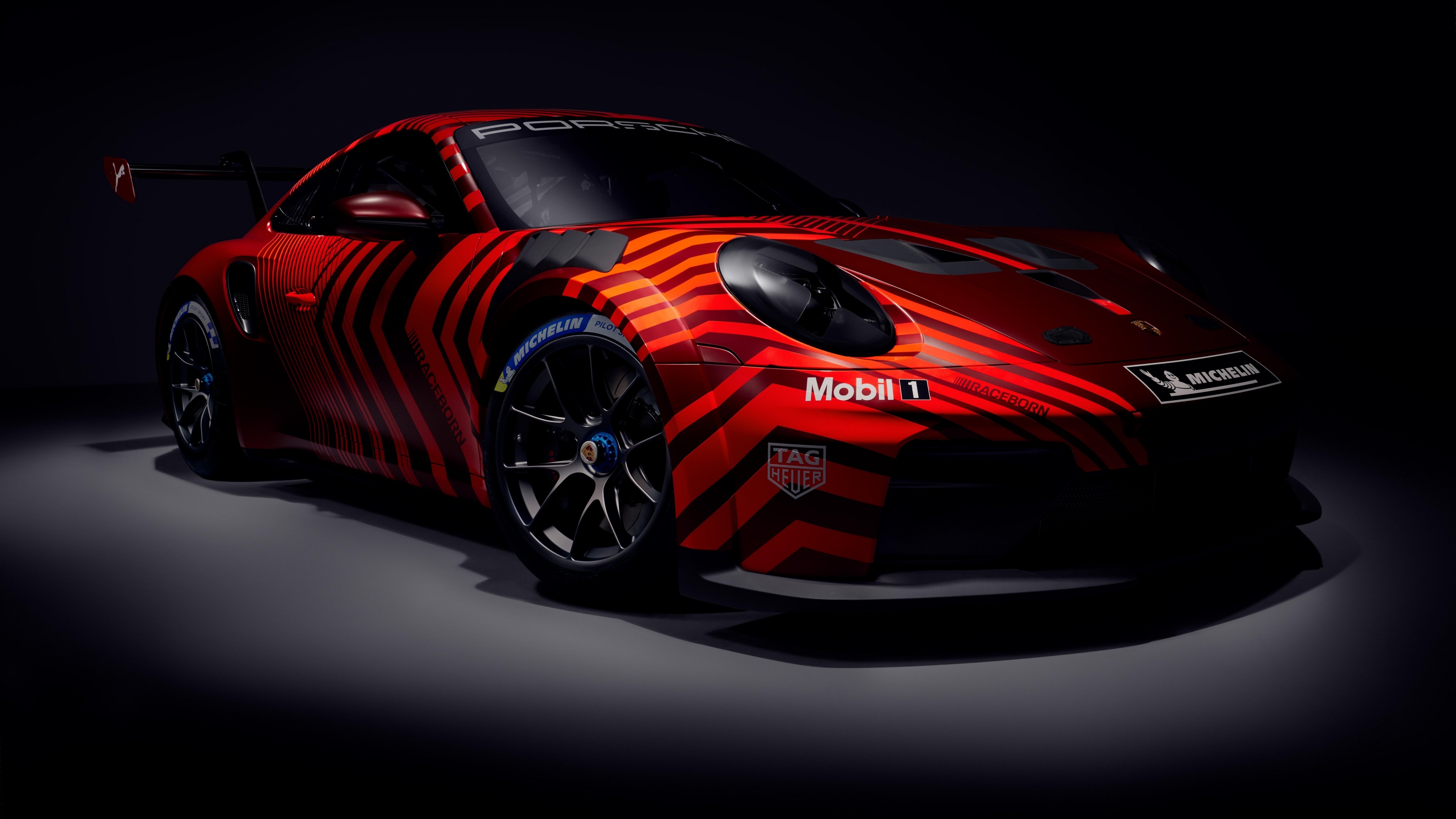 A cinematic 5K view of the 2025 Porsche 911 GT3 Cup racing car emerging from a dark, atmospheric background.