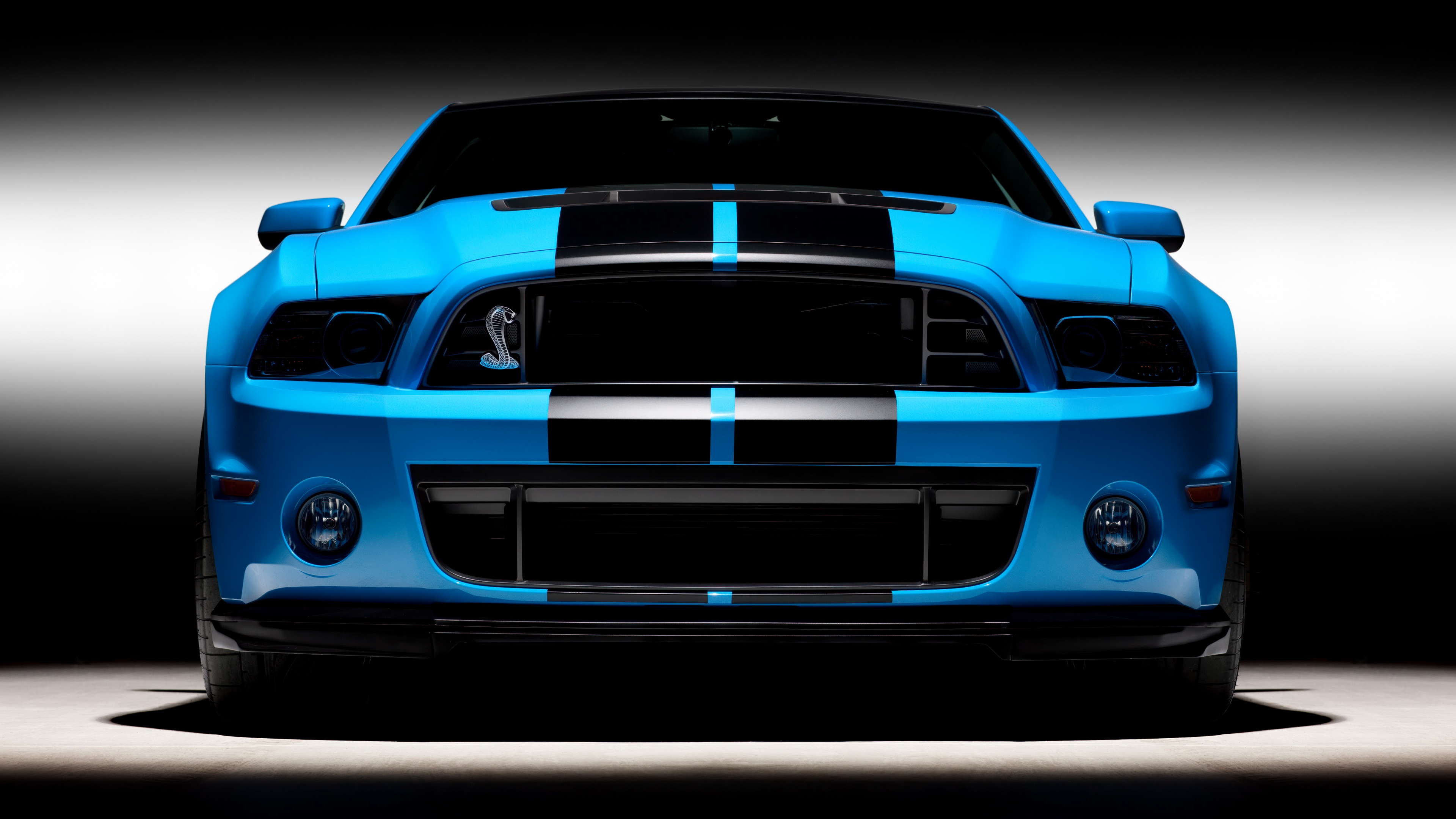 Front view of a powerful muscle car featuring iconic racing stripes and an aggressive grille.