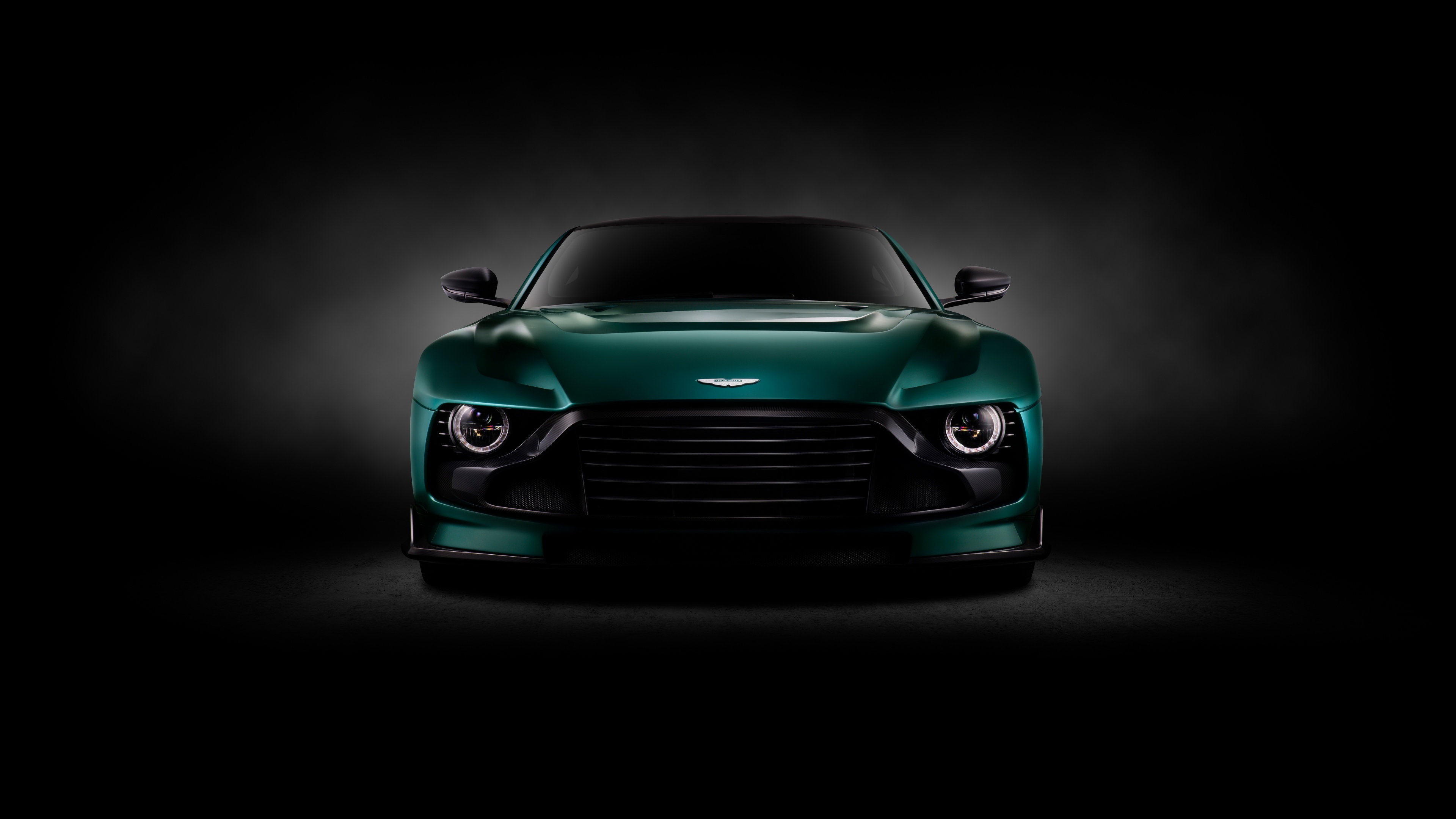A high-resolution, cinematic shot of an Aston Martin Valorem sports car against a dark, moody background.